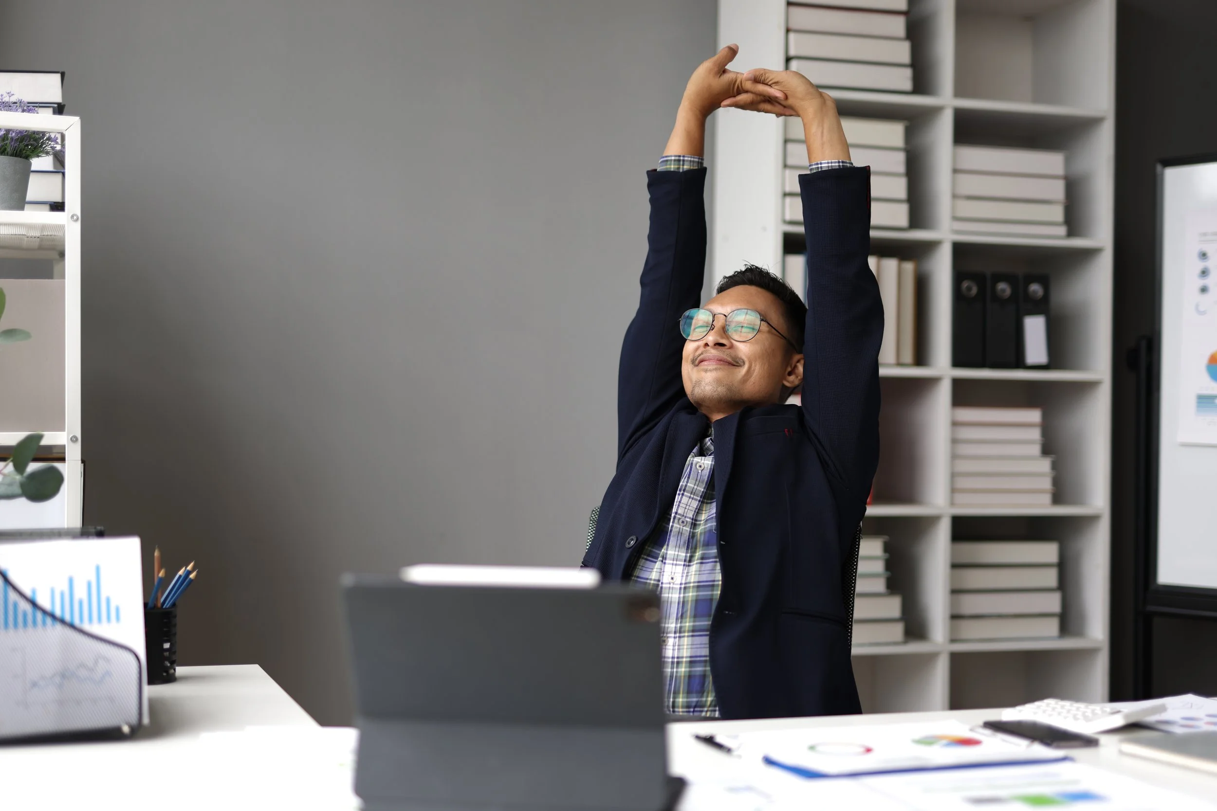 stretching arms overheaad at desk male.jpeg