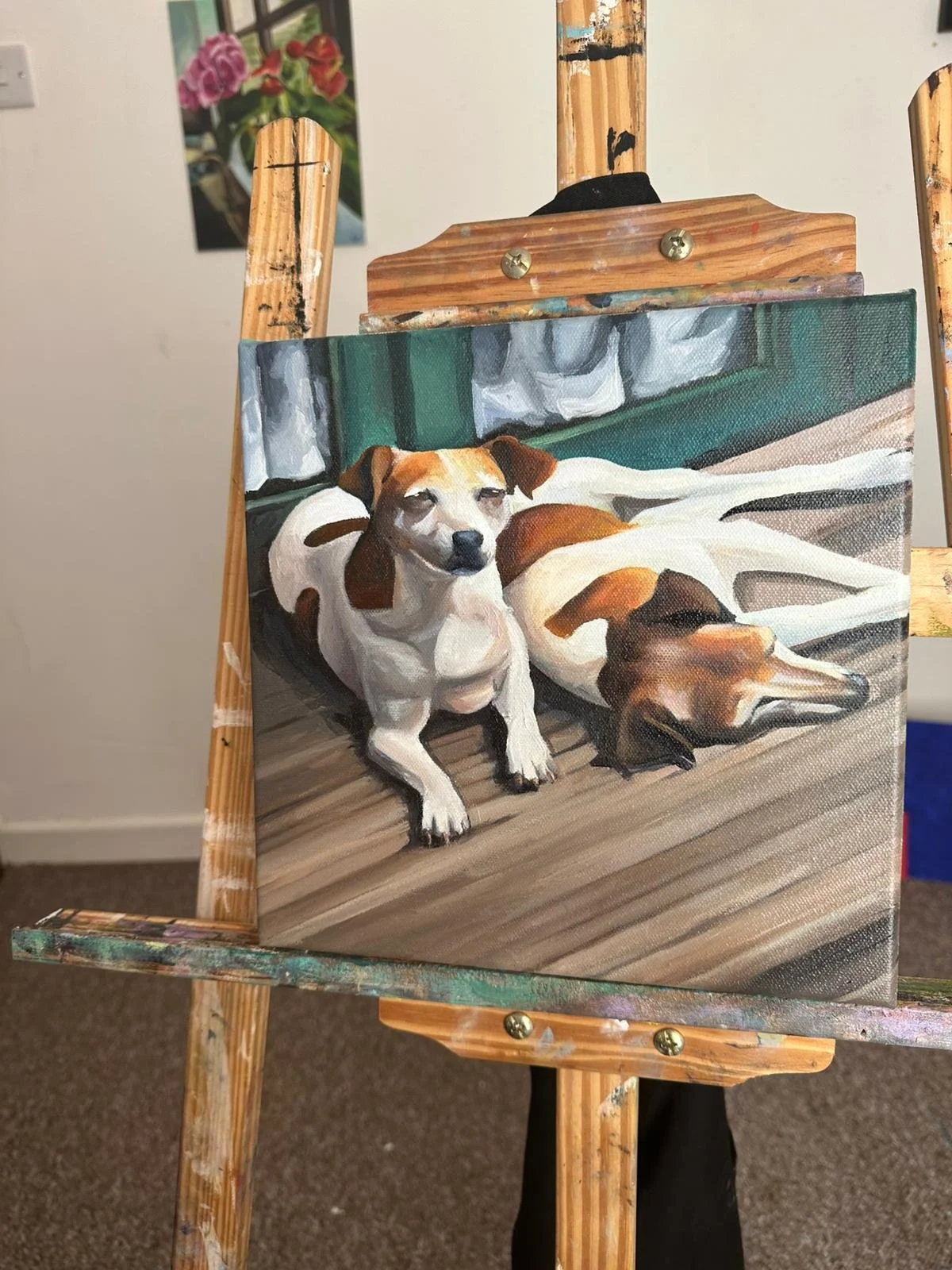 A painting of two dogs resting on a wooden deck with a background of a green window and white curtains.