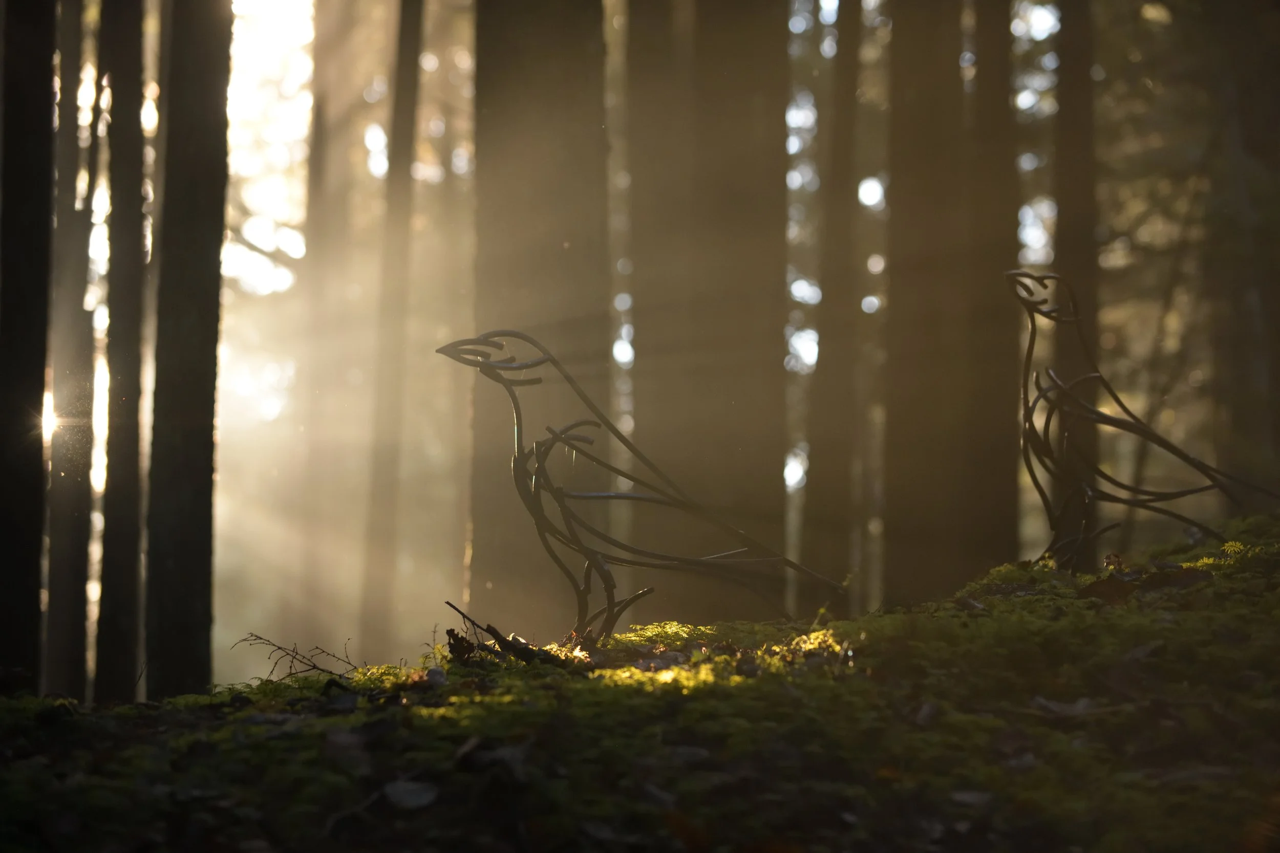 Raven sculpture basks in mystical light in the forest