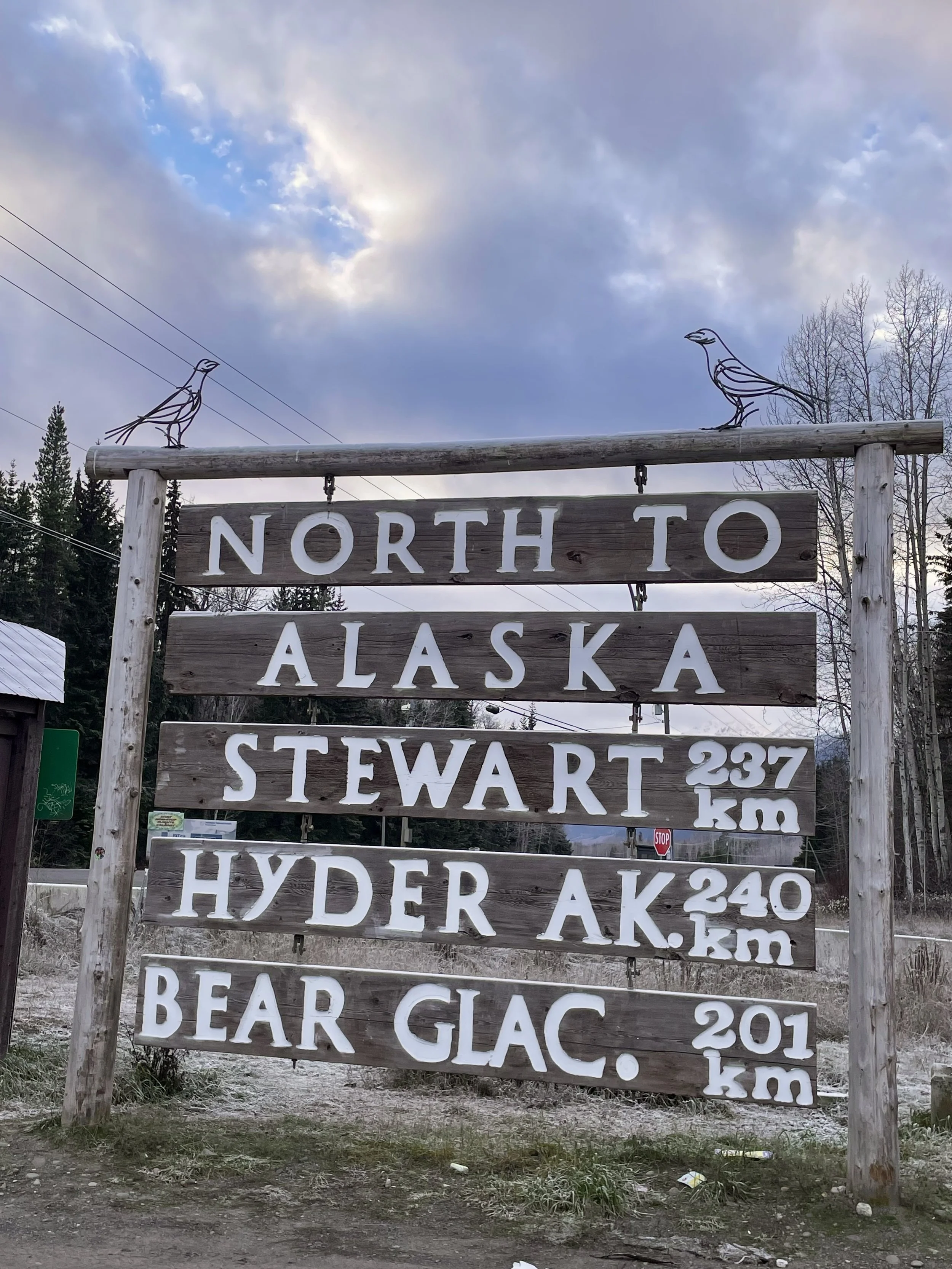 Alaska highway sign with Raven sculptures