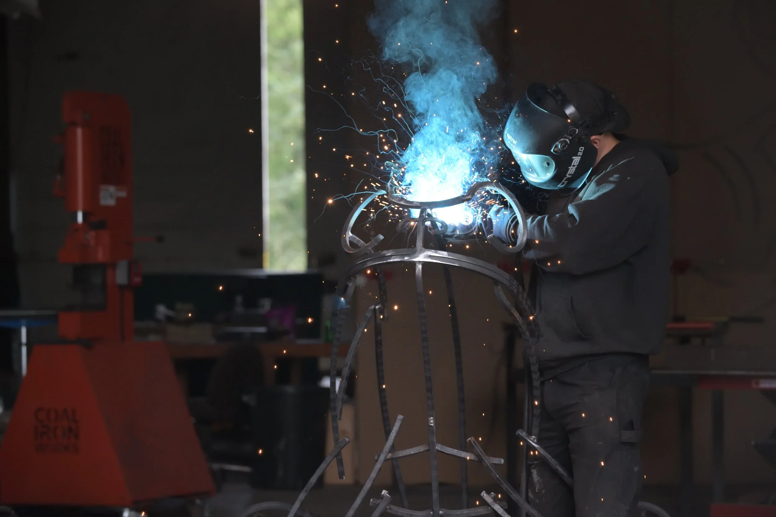 Sculptor welding on a toad sculpture