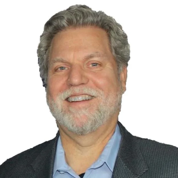 Headshot of a middle-aged man with gray hair and a beard, smiling, wearing a suit jacket and light blue shirt.
