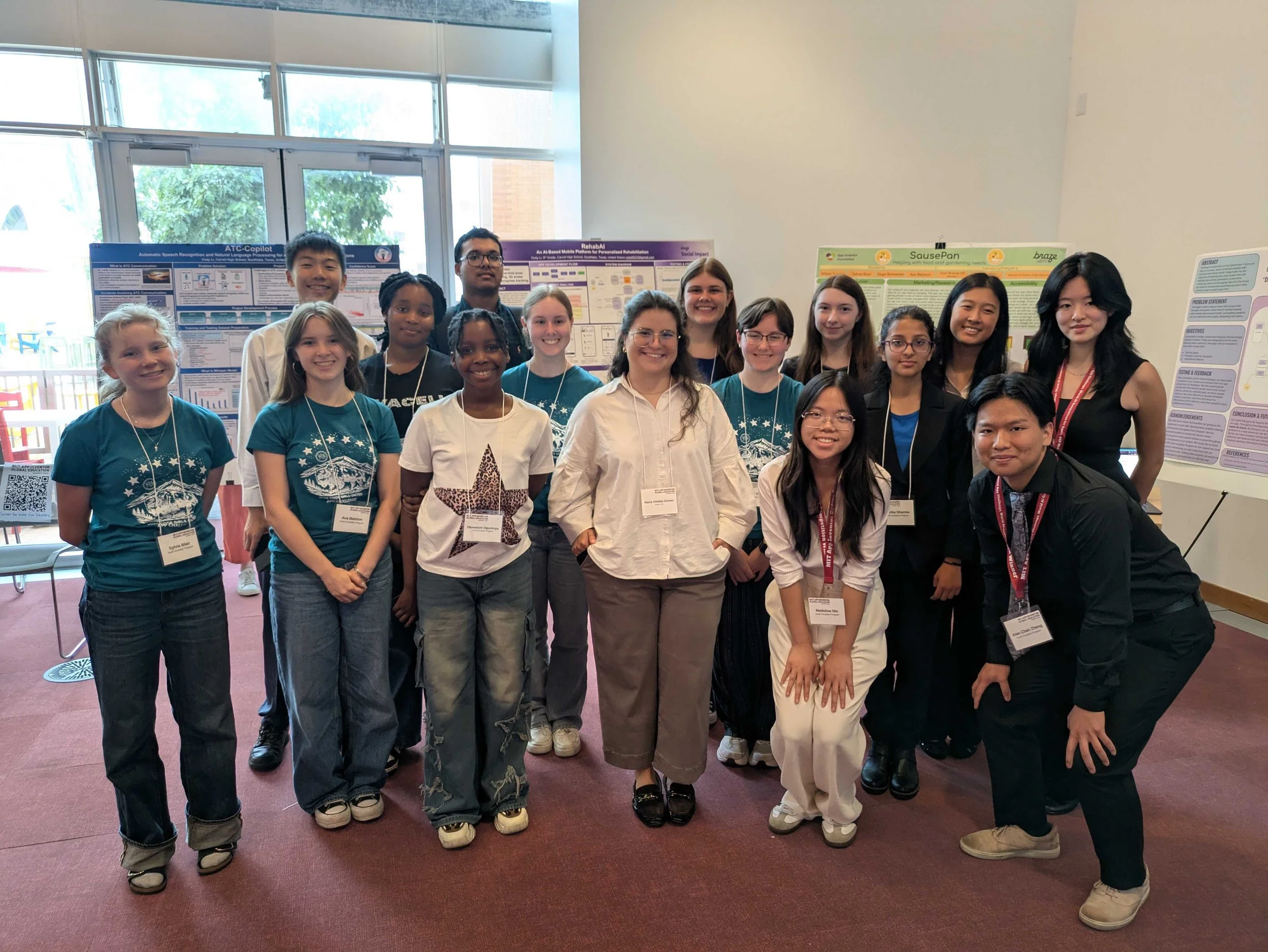 Group of young students smiling at a science or research conference, standing in front of colorful research posters.