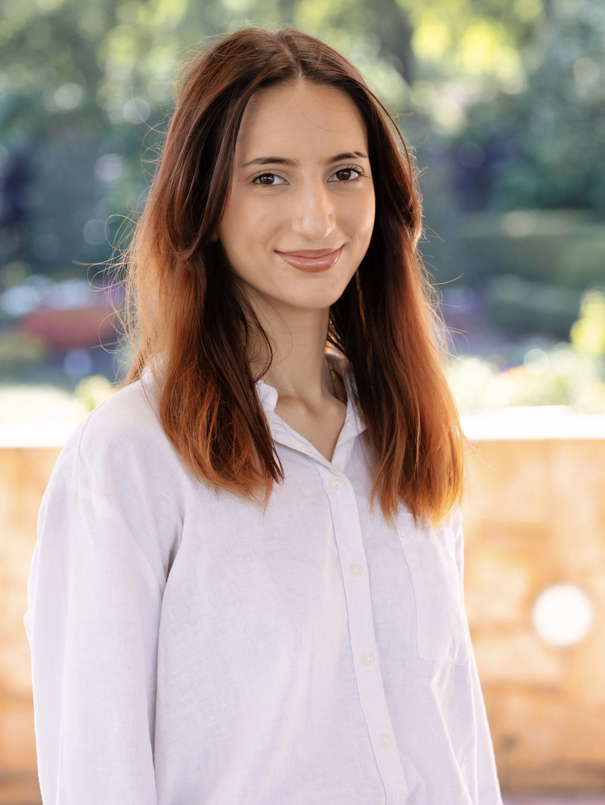 Smiling woman with reddish-brown hair wearing a white button up shirt