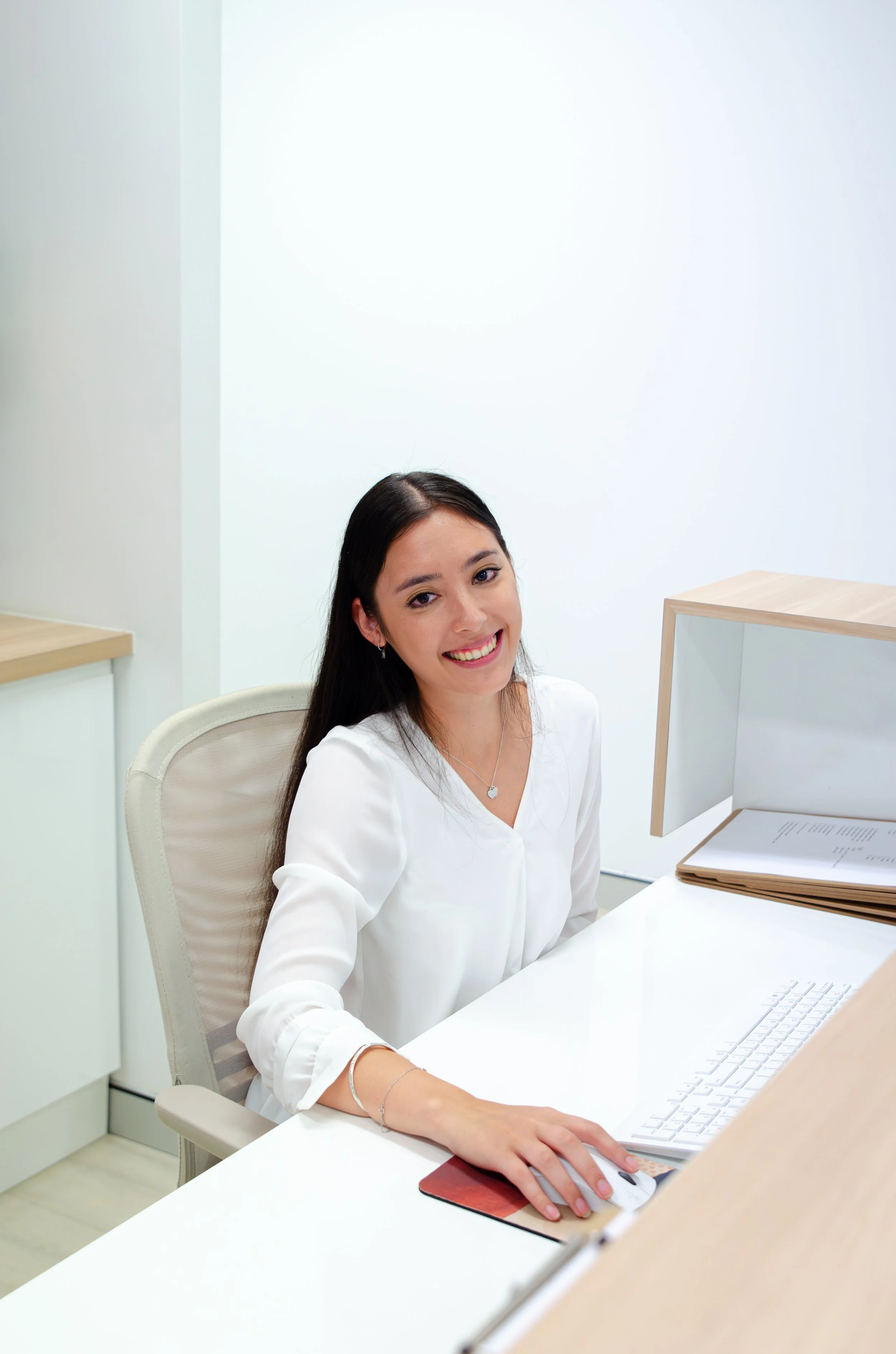 Smiling dark-haired woman wearing a white blouse