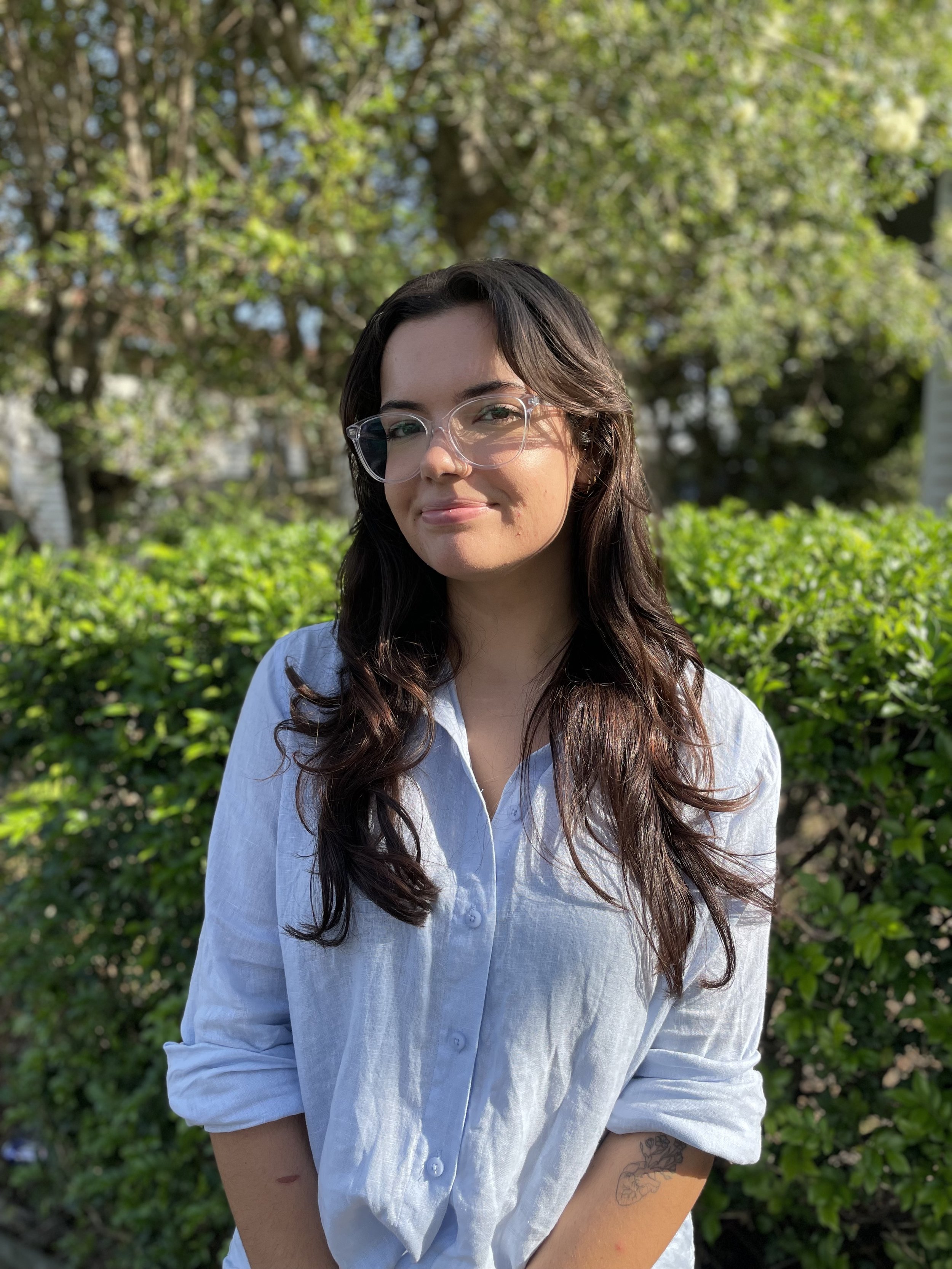 Smiling brown haired woman wearing glasses and a light blue button up