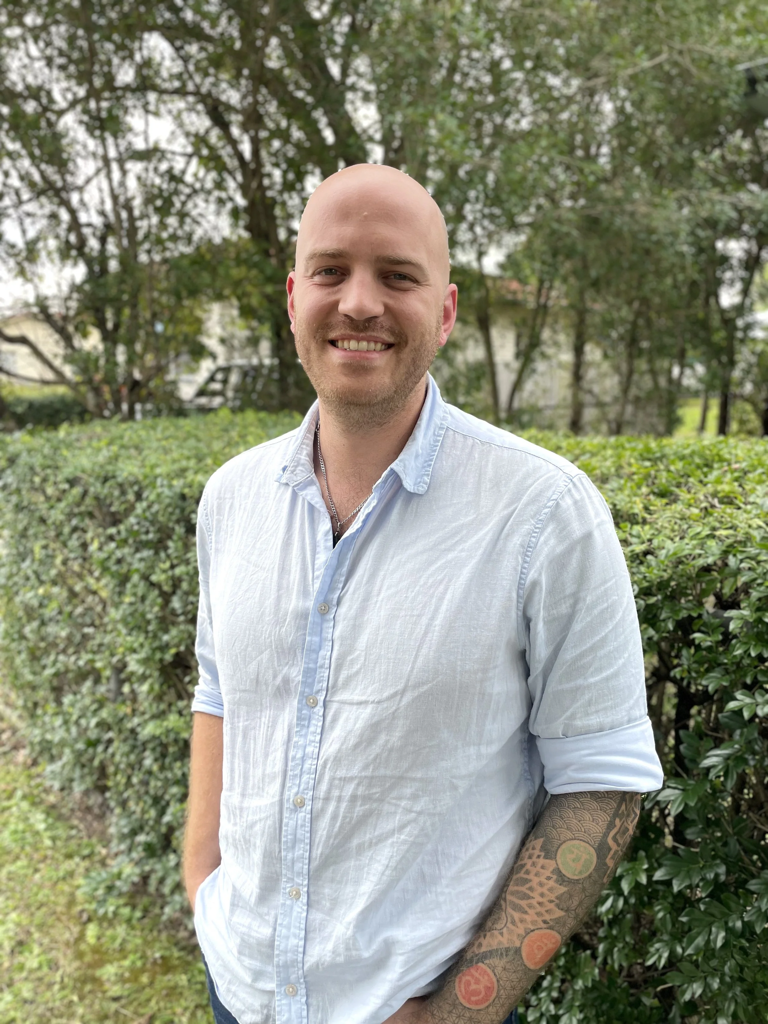 Smiling man in a white shirt standing in an office setting.