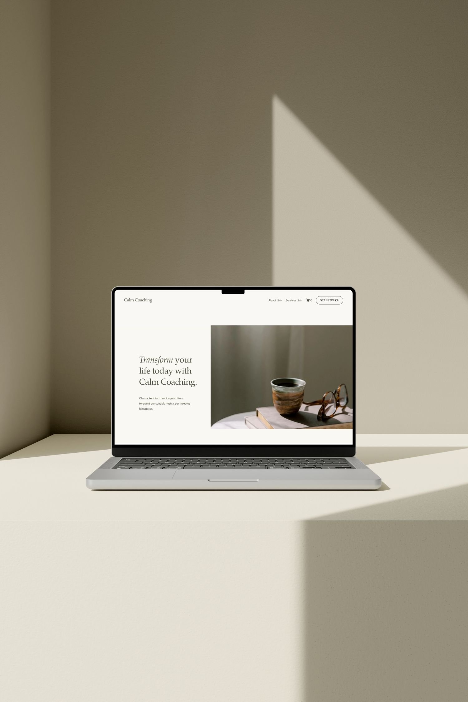 A laptop on a white desk displaying a website for Calm Coaching, with a mug, glasses, and a book on the desk in front of the laptop.