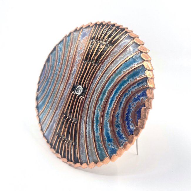 round handmade enamel cloisonné brooch with blue and green arcs and copper lines