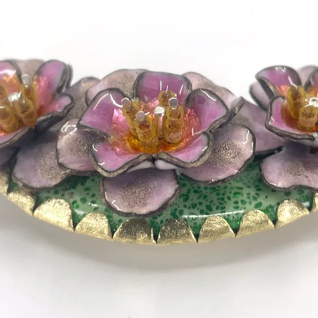 detail of pendant with enamel pink roses and green background and brass setting