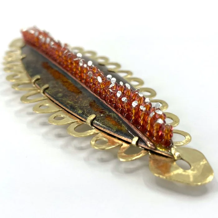 Brown and red marquise enamel brooch with pierced lacy scalloped brass setting