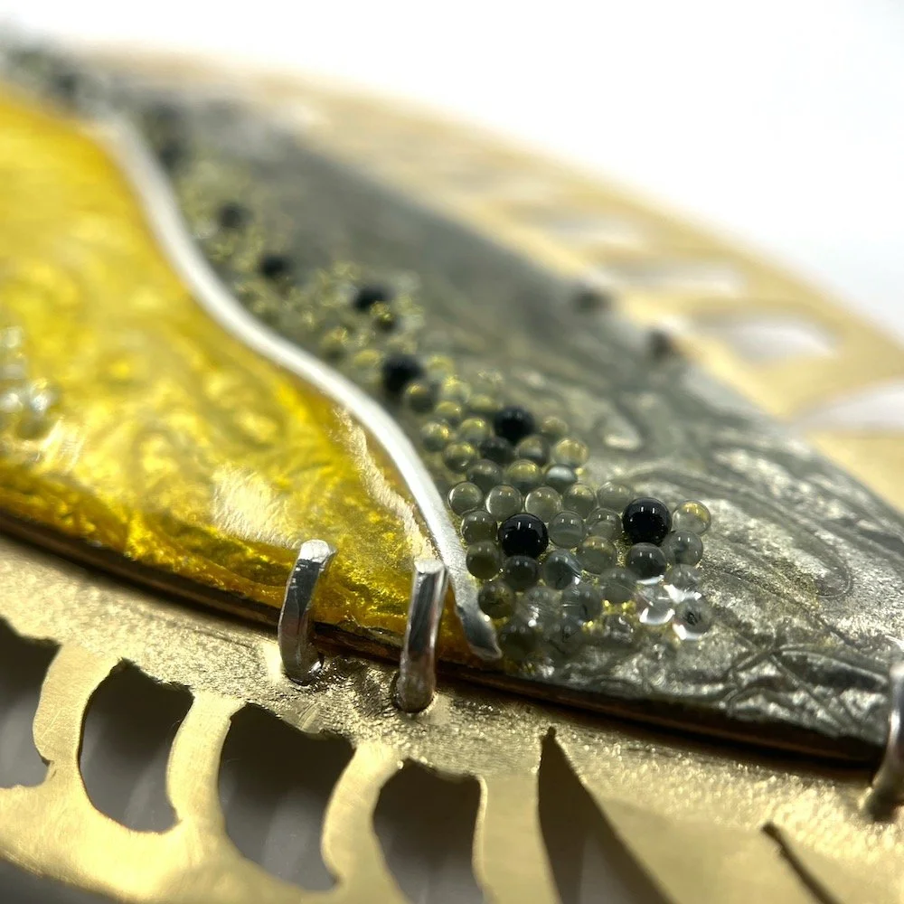 Close up of cloisonné enamel and beaded handmade fish brooch with ginbari, yellow and grays and brass