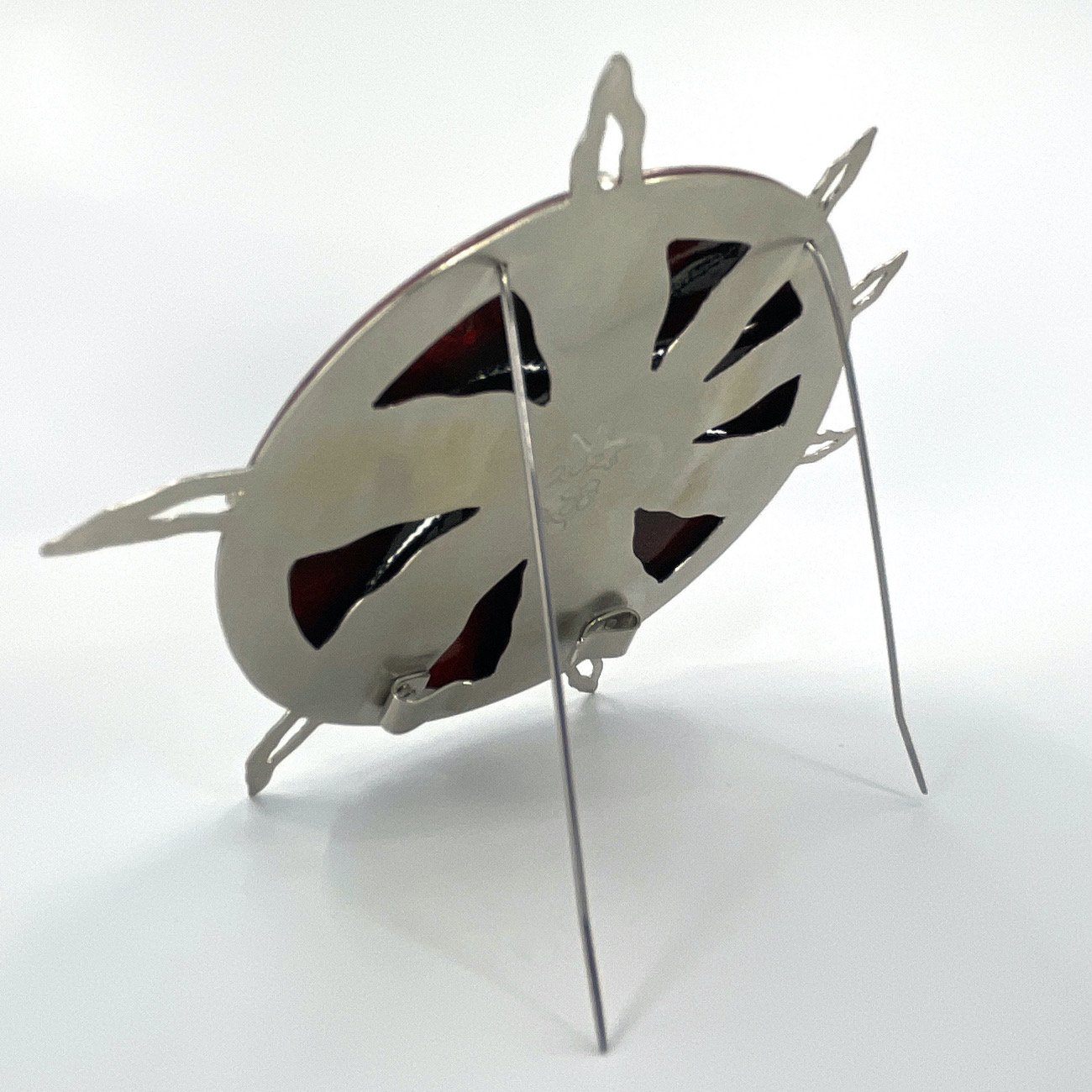 back of round handmade enamel brooch with pierced silver setting and spikes