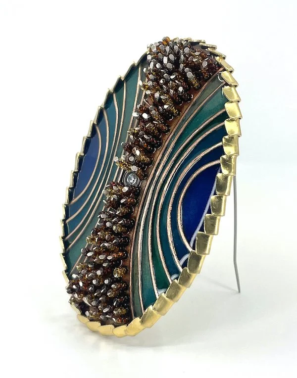 oval handmade cloisonné  enamel brooch with blue and green arcs and amber beads and brass setting