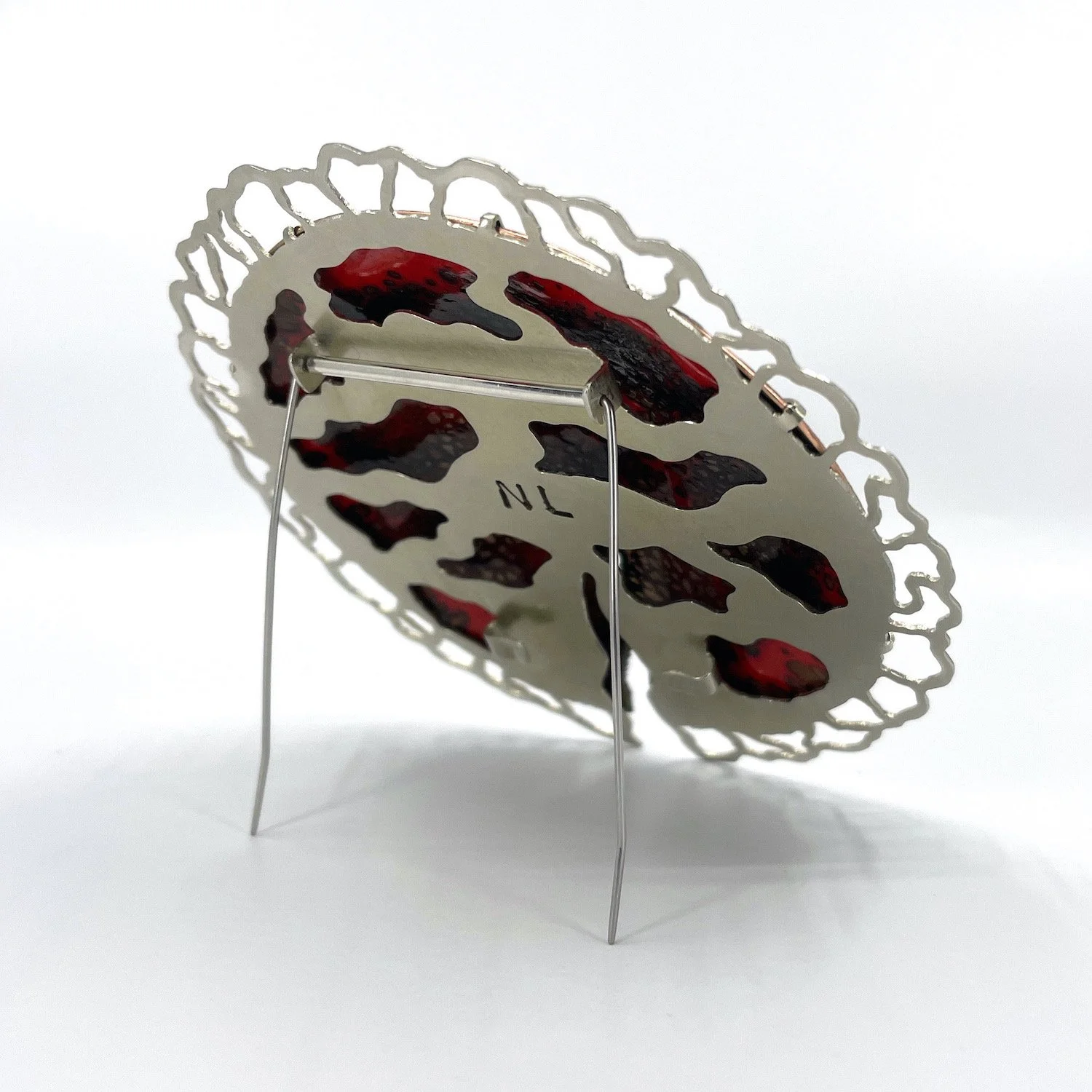 back of round handmade enamel brooch with red back and lacy silver setting