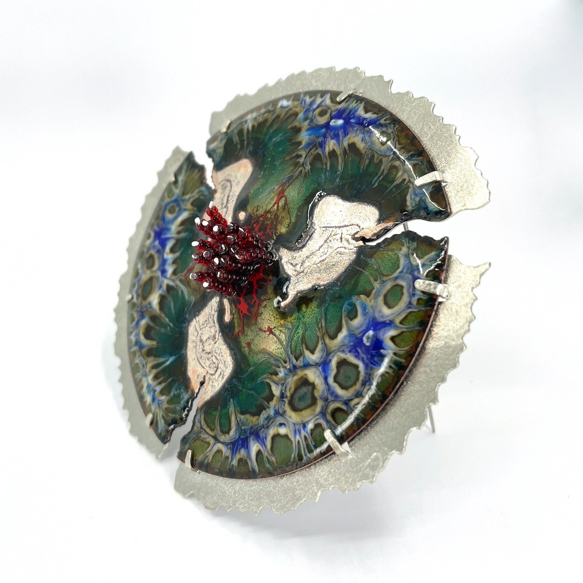 round handmade enamel brooch with blue and green and silver organic pattern and red beads