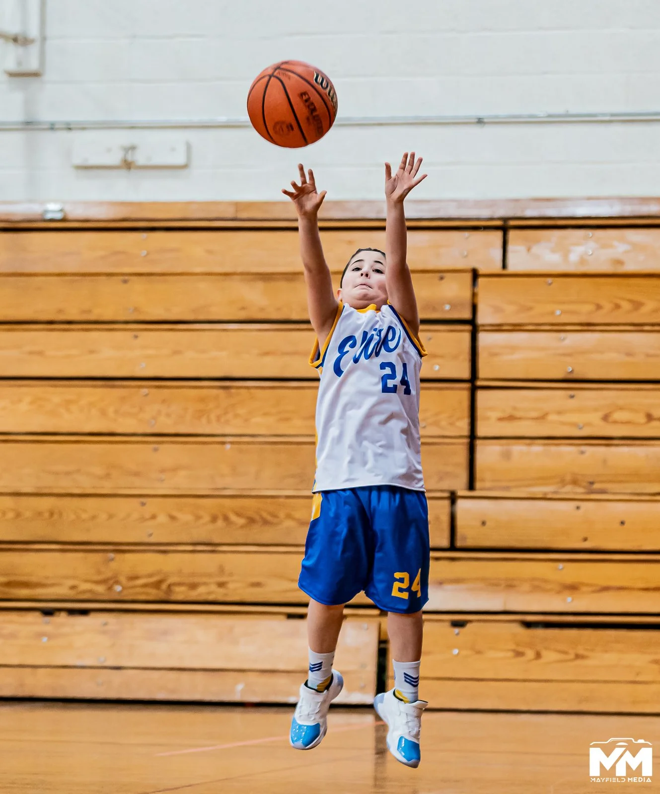 Young basketball players practicing shooting and passing in an indoor gymnasium.
