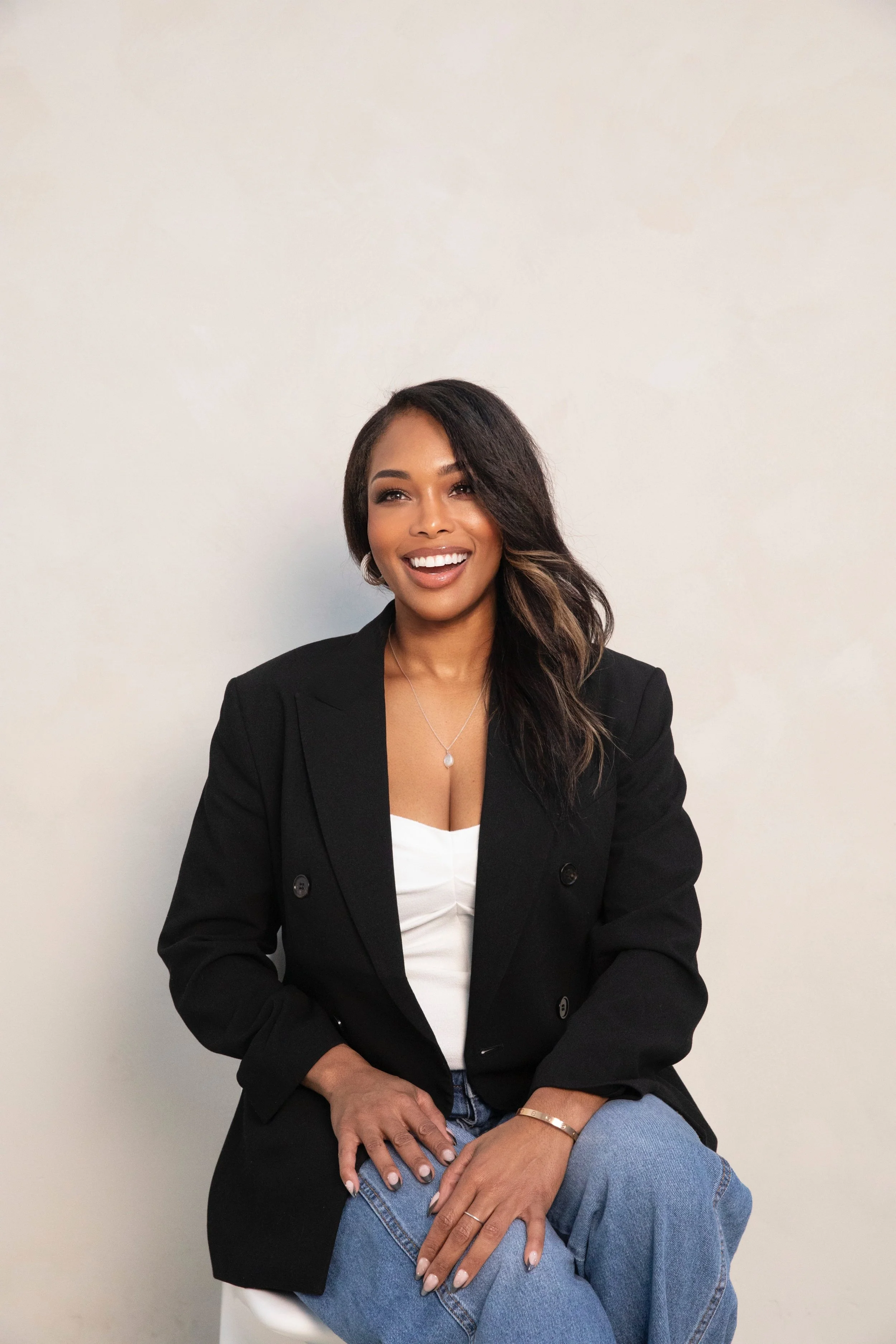 Woman smiling in a black blazer, wearing a white blouse