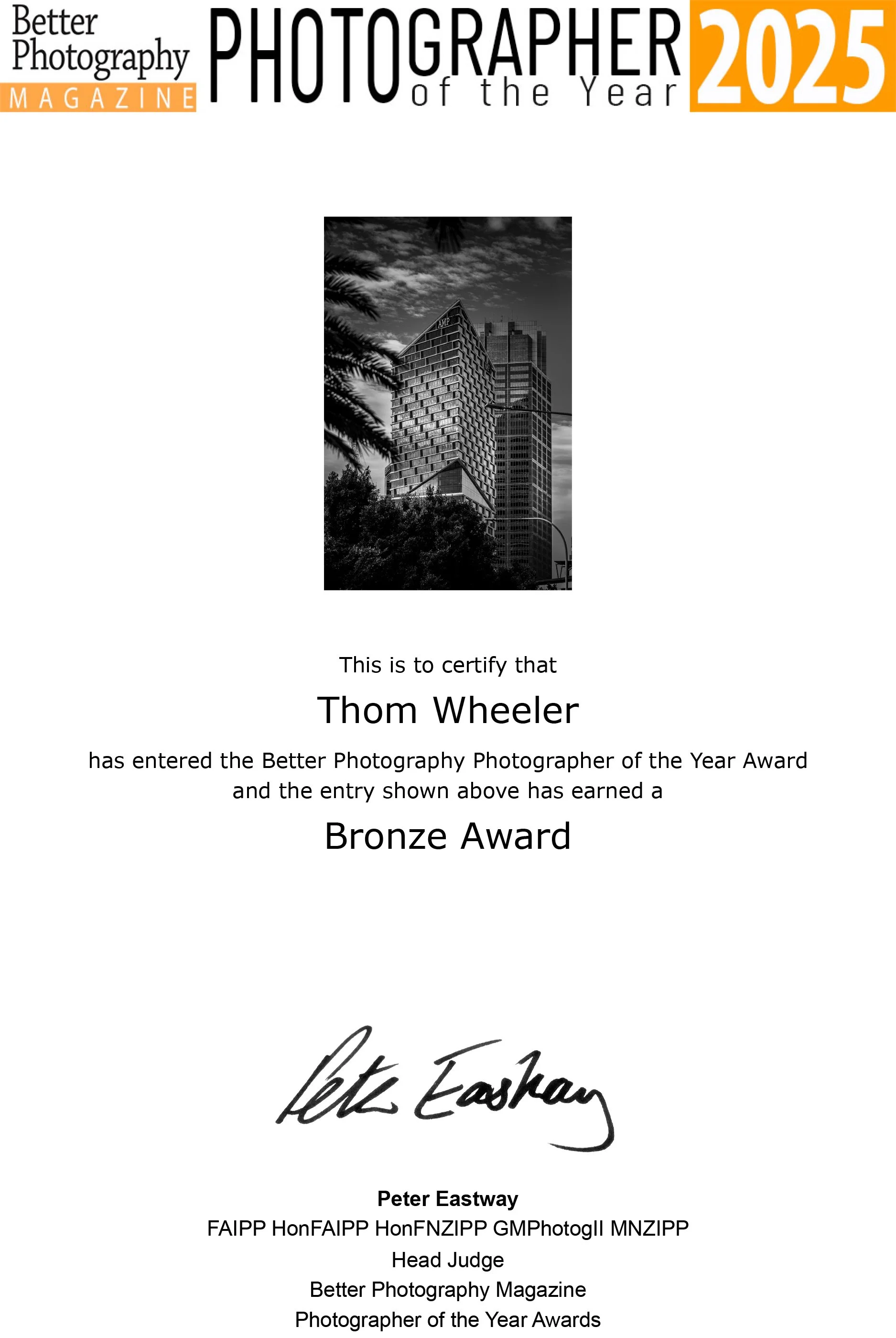 Black and white certificate awarding Thom Wheeler the Bronze Award in the Better Photography Photographer of the Year 2025 contest, signed by Peter Eastaway, featuring a photo of a modern high-rise building with a cloudy sky and trees in the foreground.