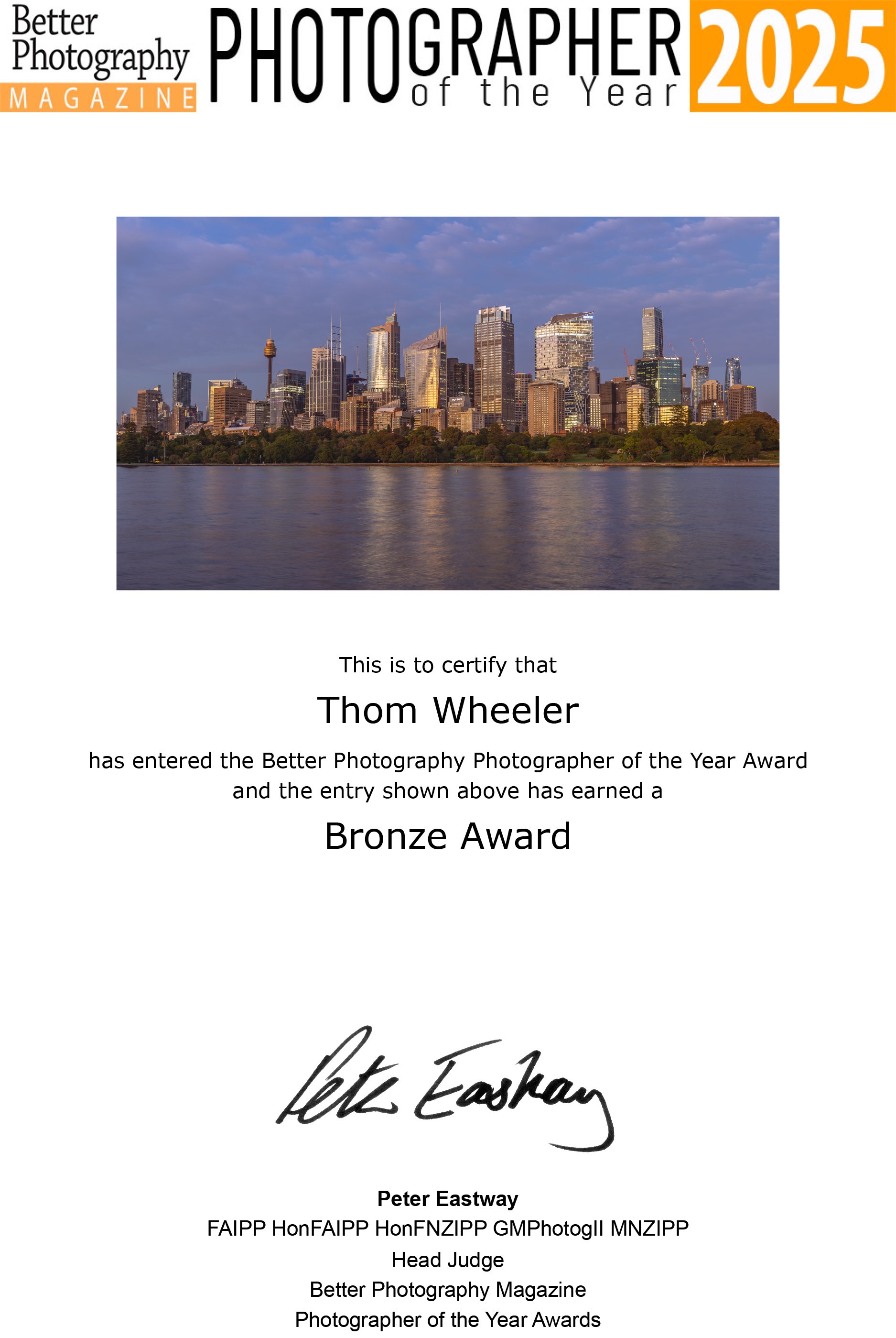 Certificate of Achievement awarded to Thom Wheeler for entering the Better Photography Photographer of the Year 2025, featuring a city skyline with skyscrapers and a water reflection.