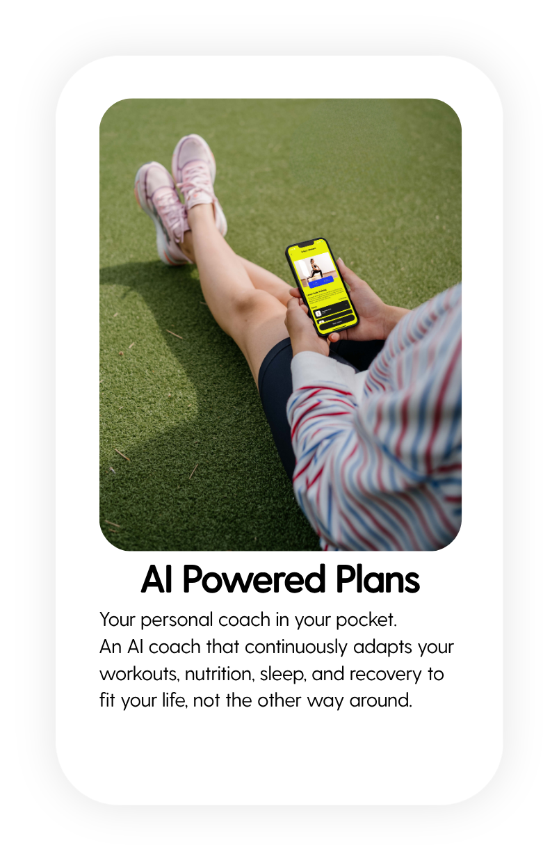 Person sitting on artificial grass floor, using a smartphone with CoachAI fitness app.
