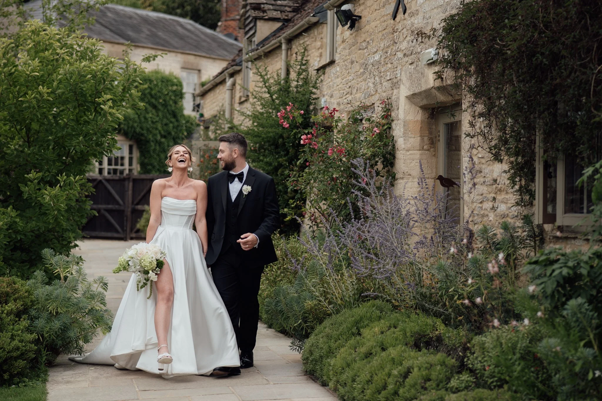 Bride and groom laughing while walking through the gardens at Caswell House, editorial Cotswolds wedding photography by Aleksandra Filipek