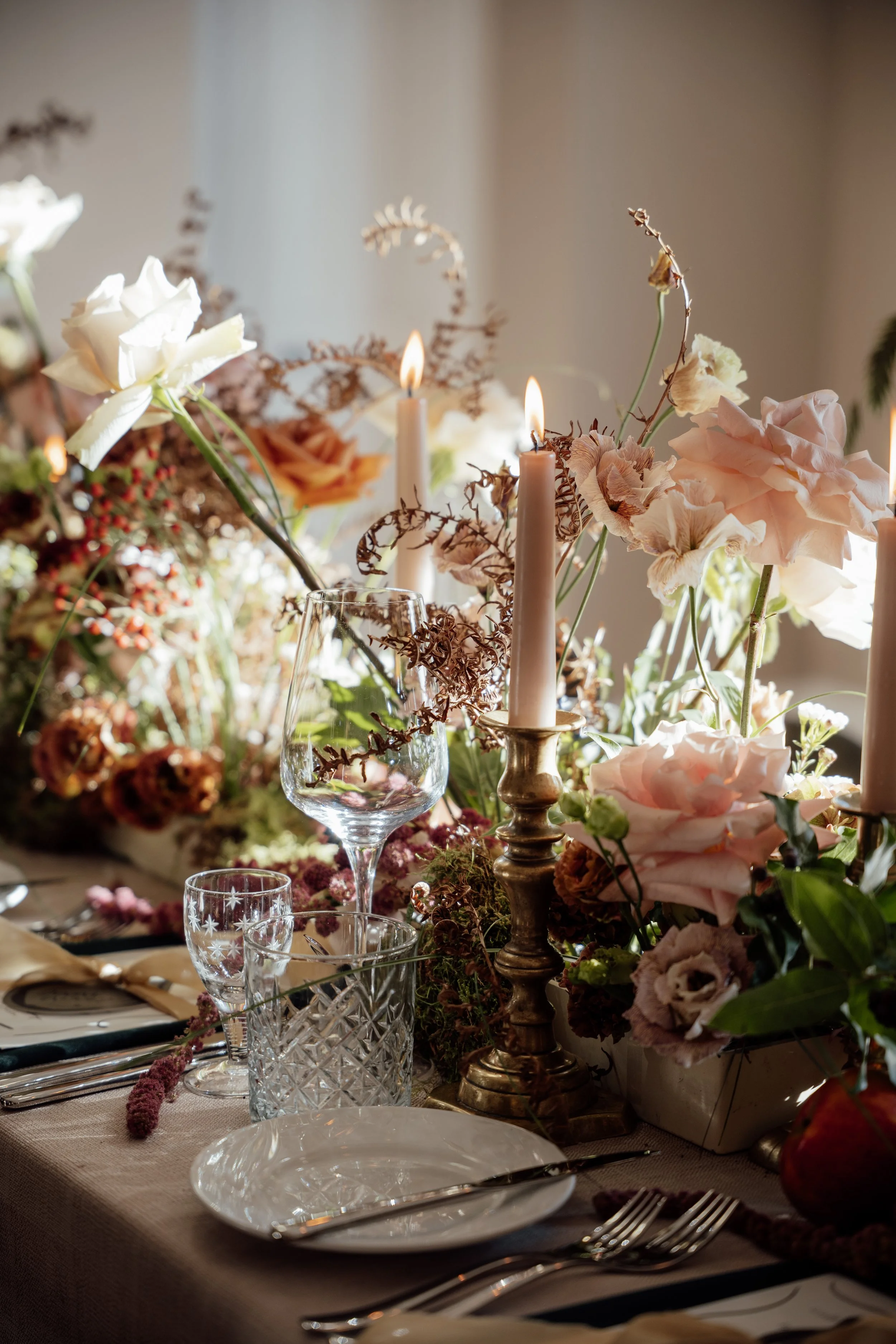 An elegantly styled wedding reception table with soft florals, candles and refined tableware creating a warm, romantic atmosphere..