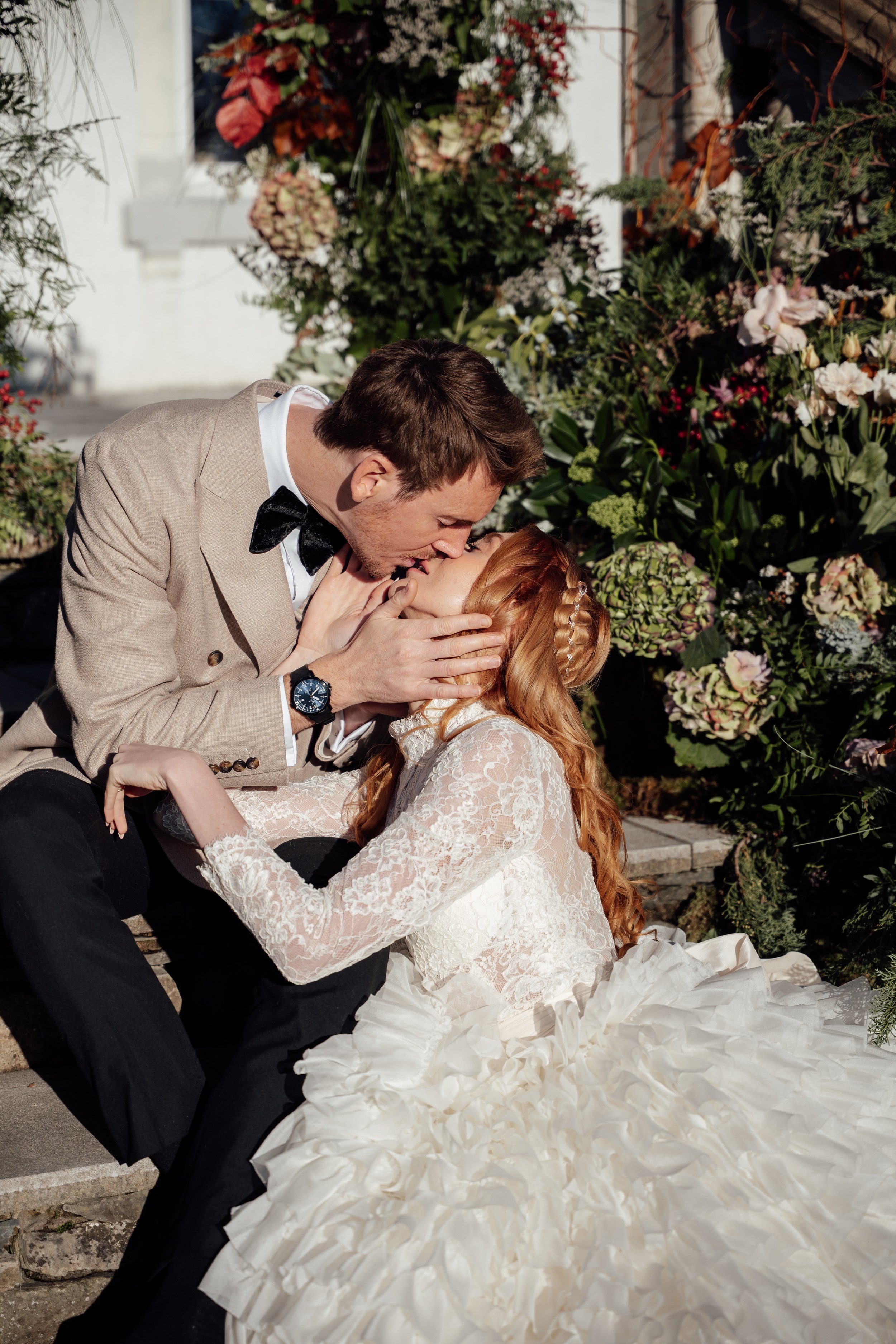 Romantic wedding moment at Cartmel Old Grammar House with the couple embracing on the steps framed by rich, colourful florals.