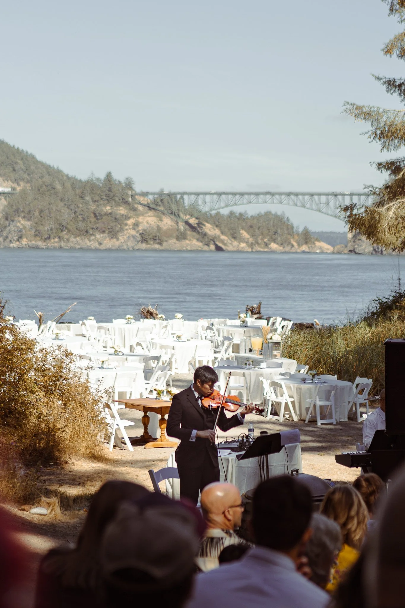 An outdoor wedding celebration overlooking water and a bridge.