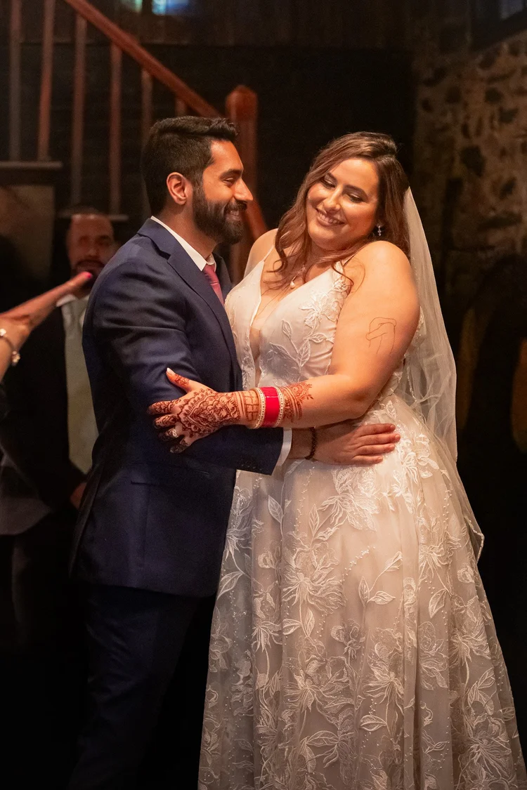A wedding couple smiling at each other on the dance floor.
