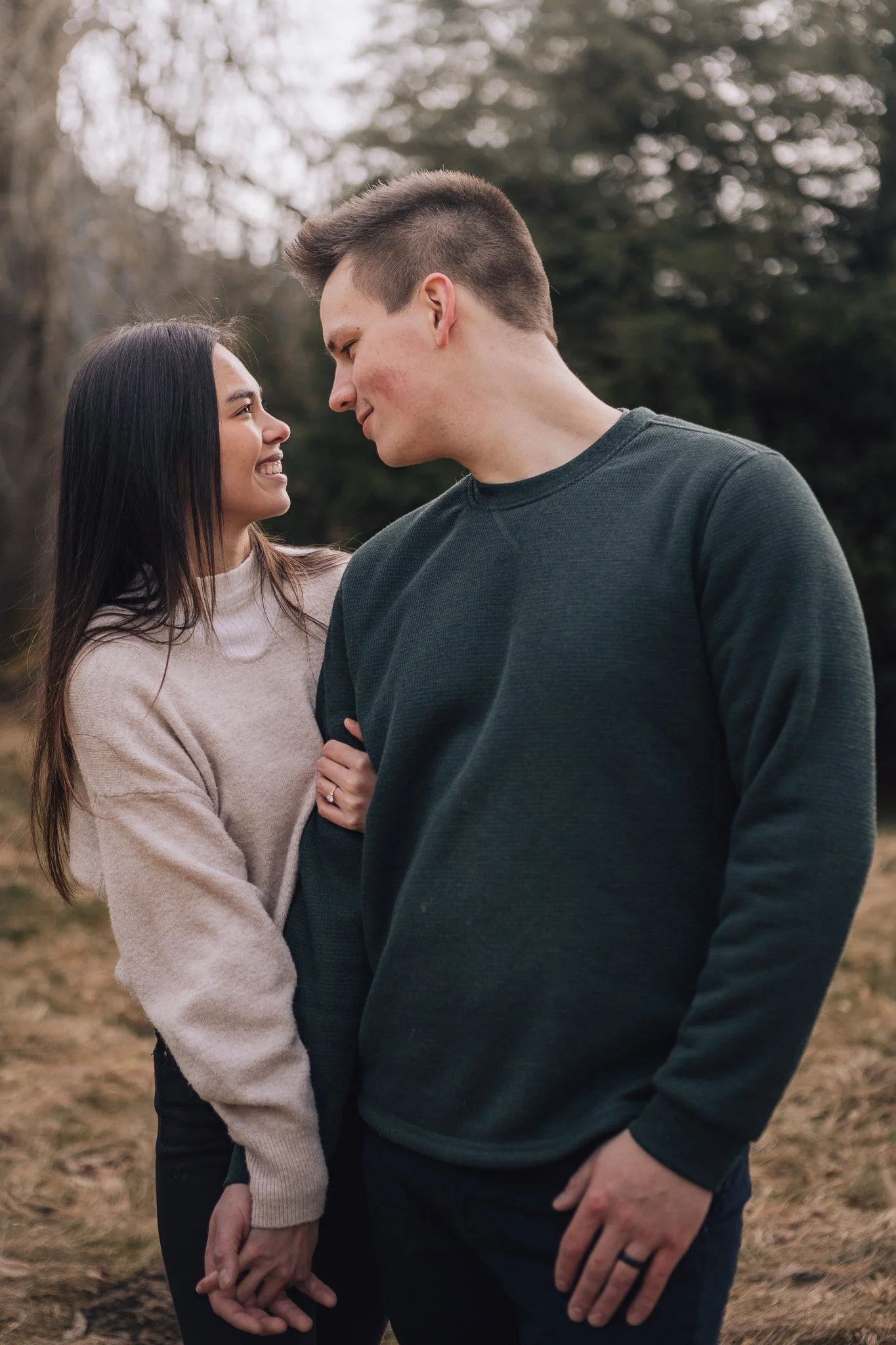 A couple leaning close together in a wooded park.