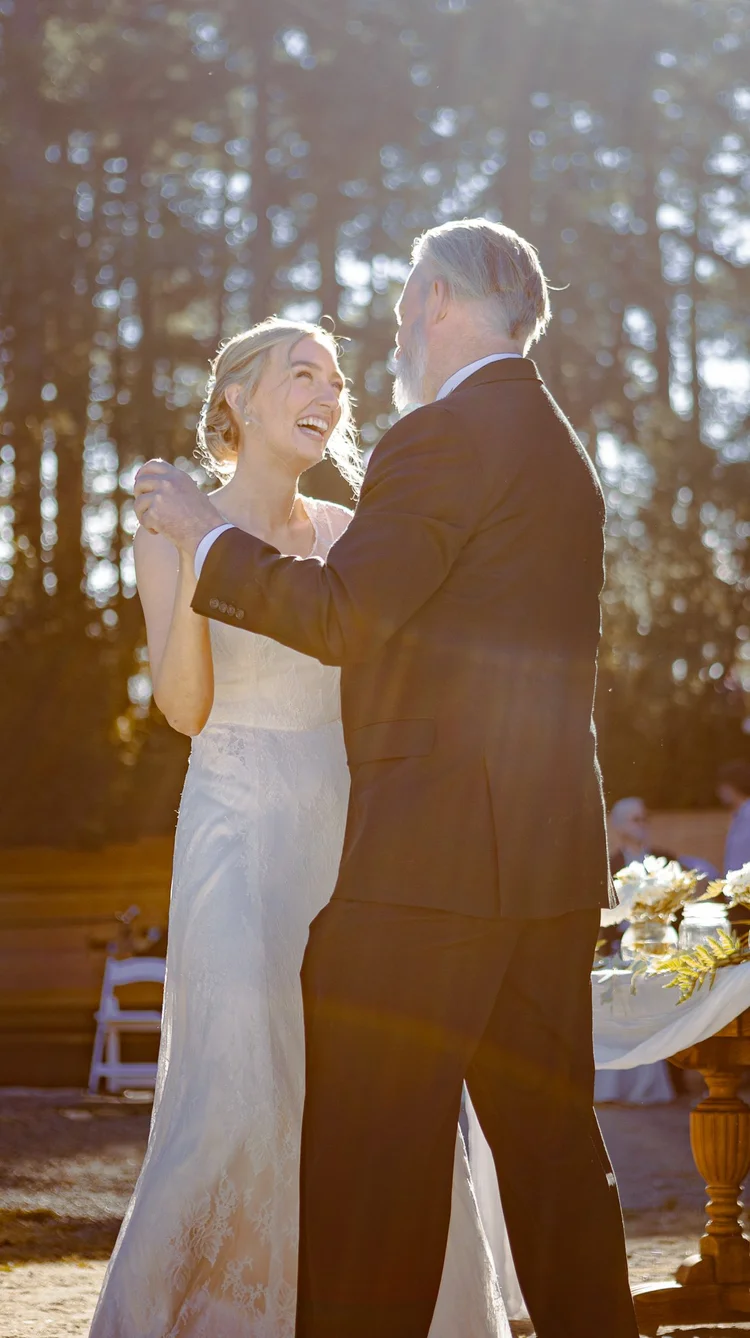 A wedding couple dancing outdoors in the sunlight.