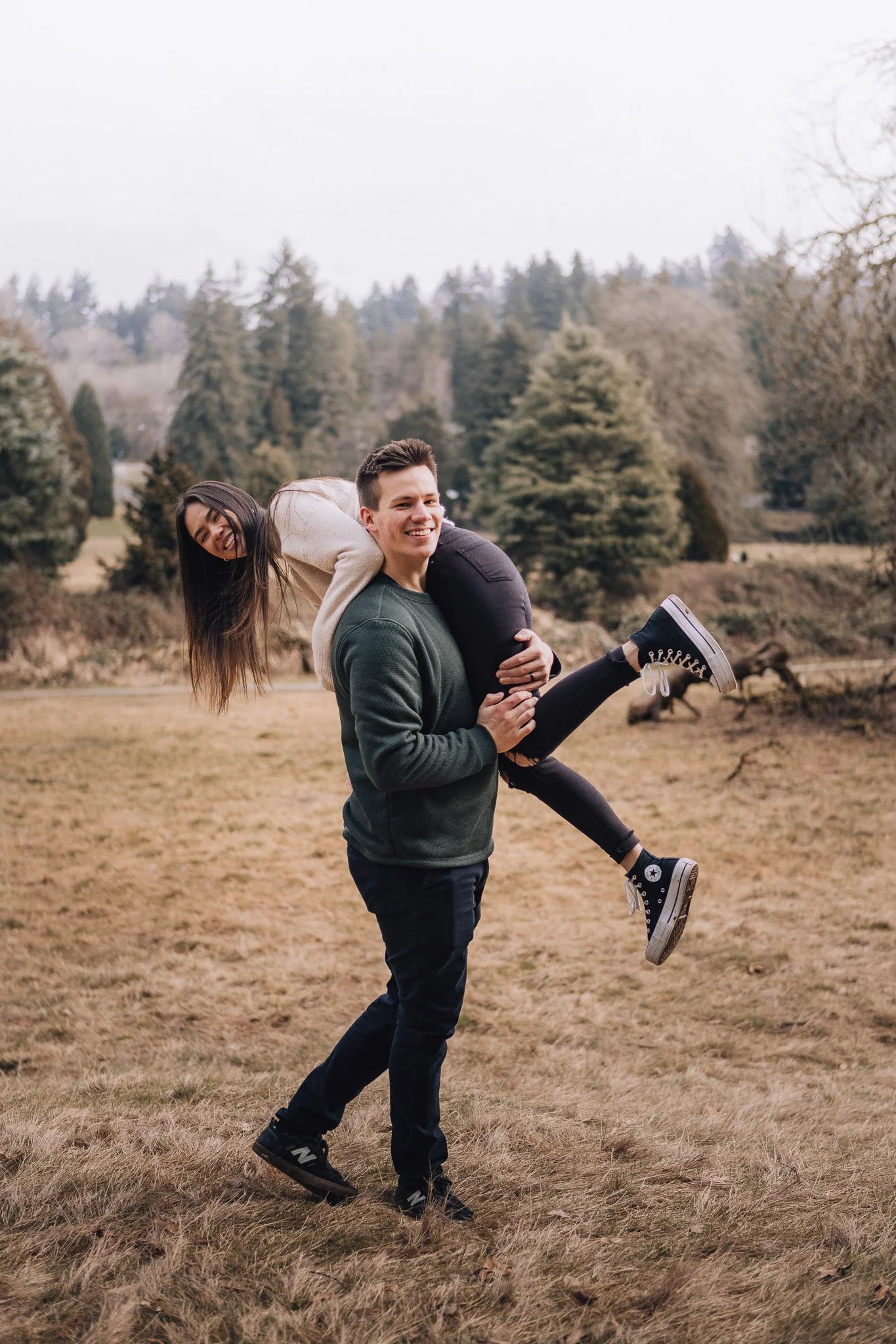A smiling couple sharing a piggyback ride in a grassy field.