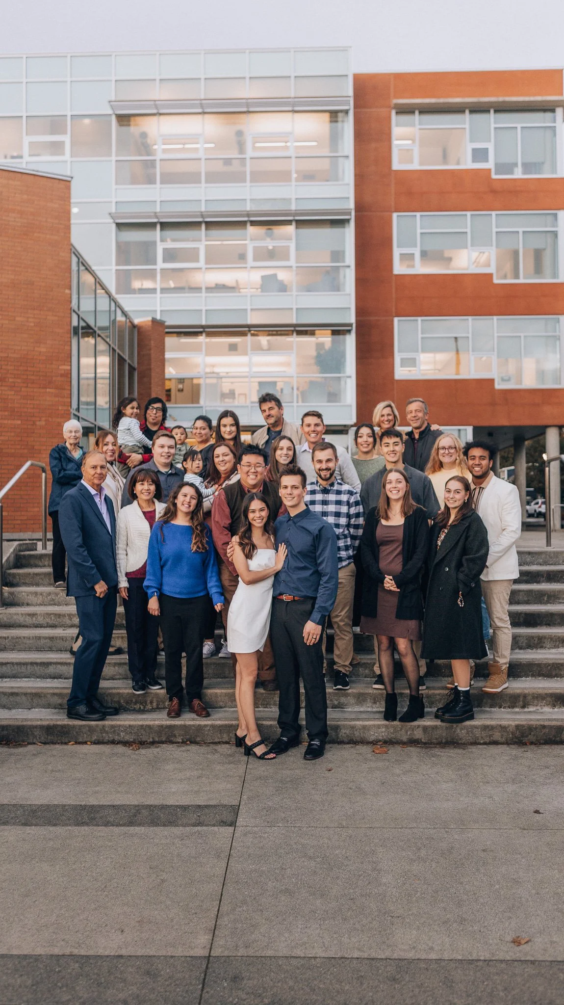 A group portrait on outdoor steps in front of a brick and glass building.