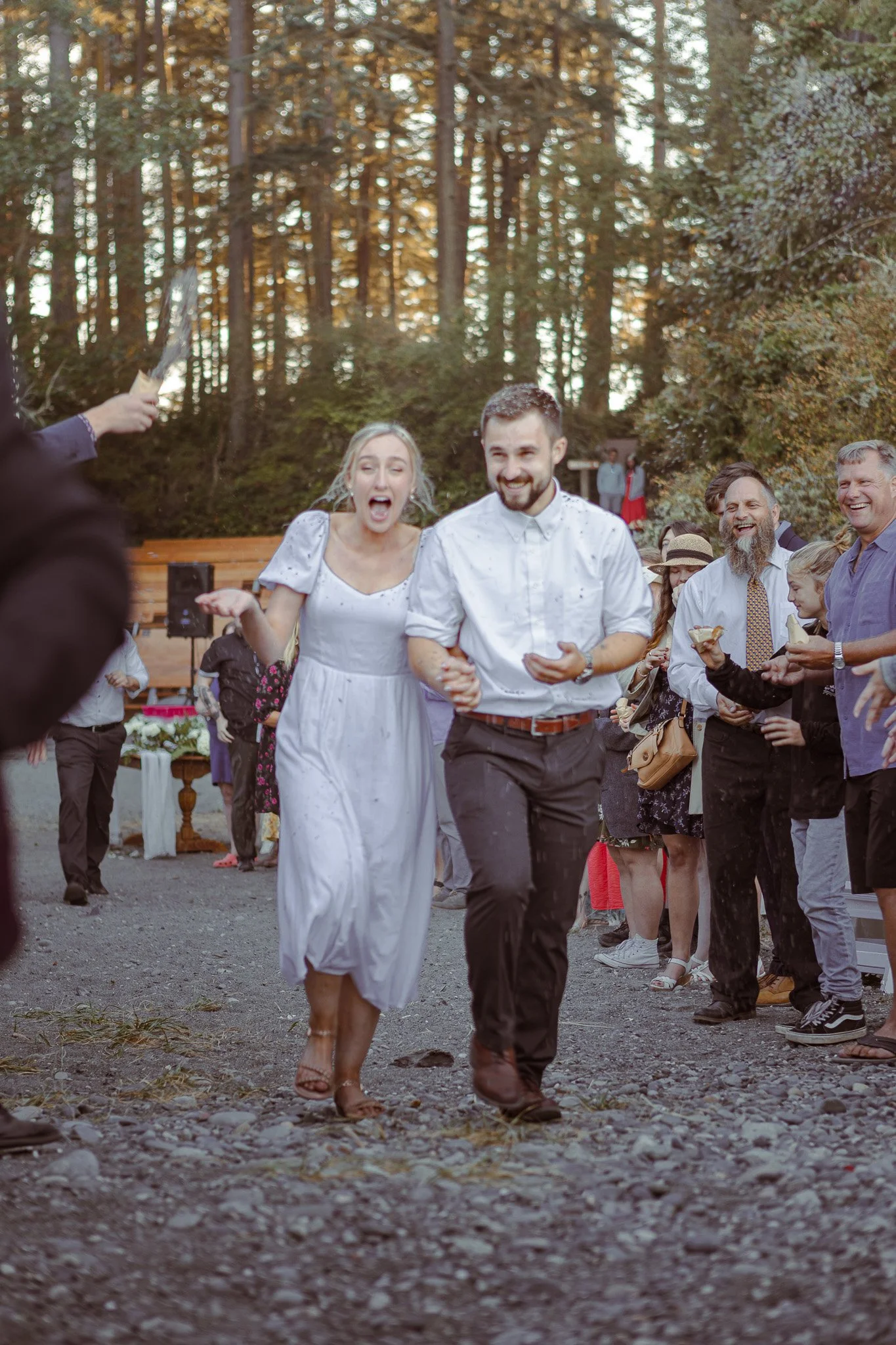 A wedding couple walking hand in hand among their guests.