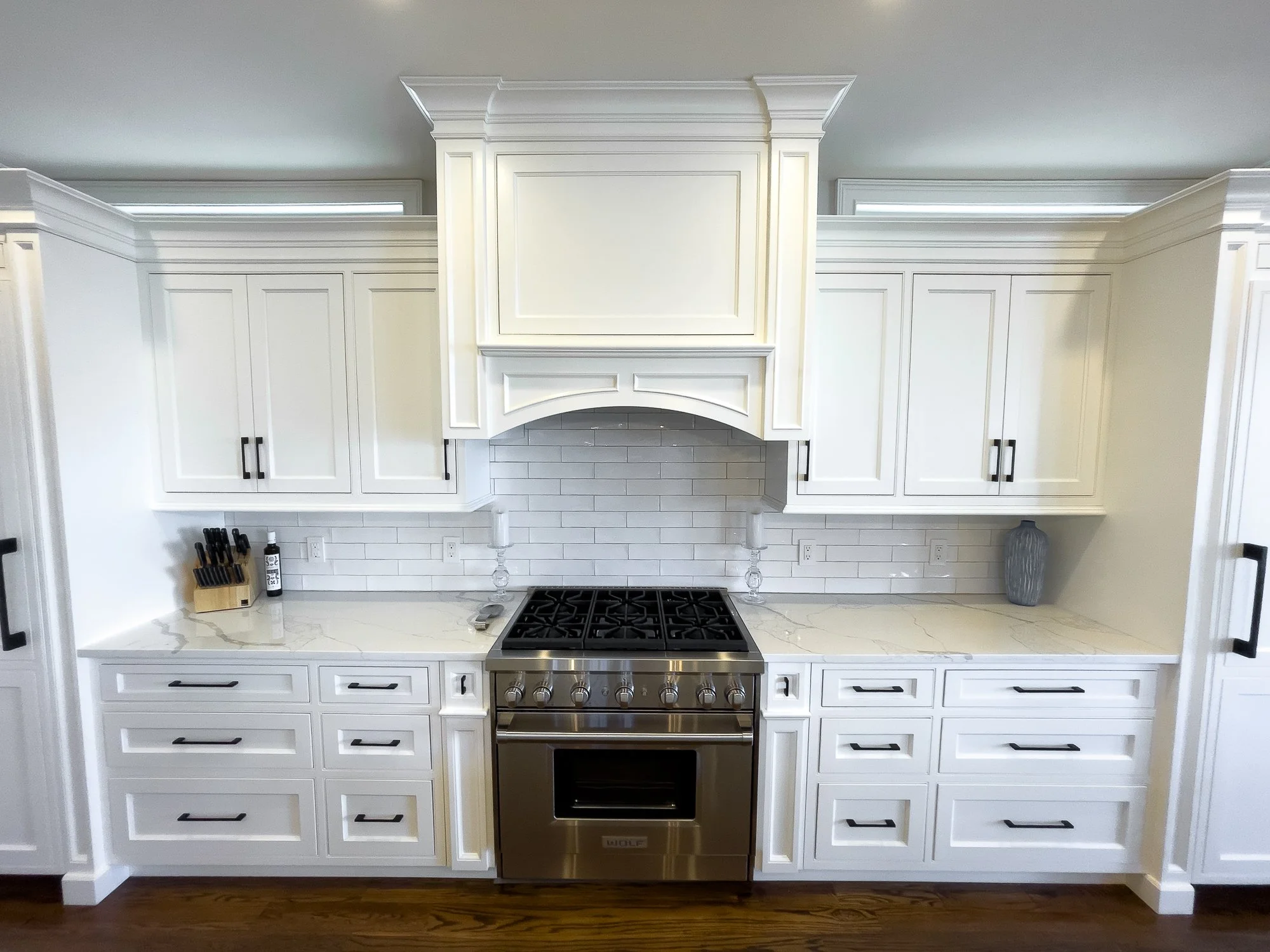 Spacious kitchen with natural light, featuring white shaker cabinets, granite countertops, a large island with bar stools, and stainless steel appliances.