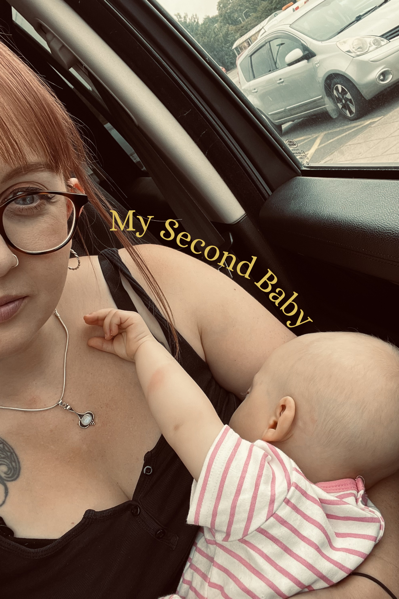A woman with glasses and a necklace is lying in a car seat with a baby. The baby, wearing a pink and white striped outfit, is reaching out and touching the woman's face. The text "My Second Baby" is overlaid on the image. Behind them, through the car window, there is a parking lot with a silver car and some trees in the background.