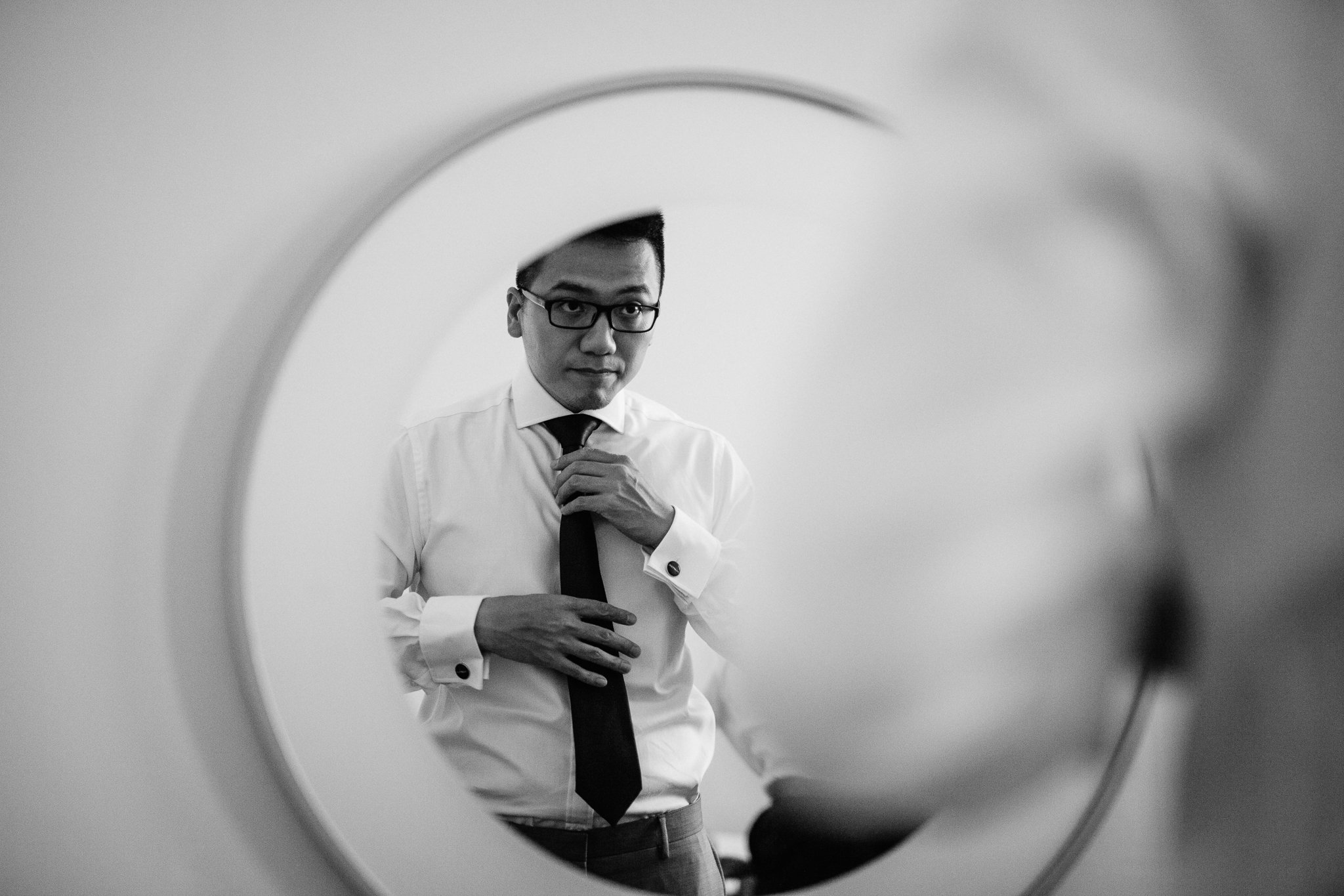  A groom looks in the mirror as he gets ready for his wedding day. 