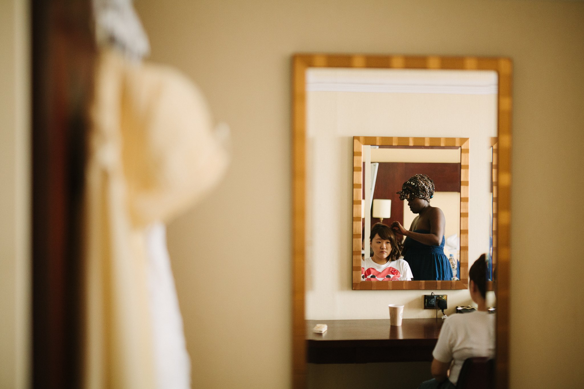  Bridesmaid having hair done looking in a mirror 