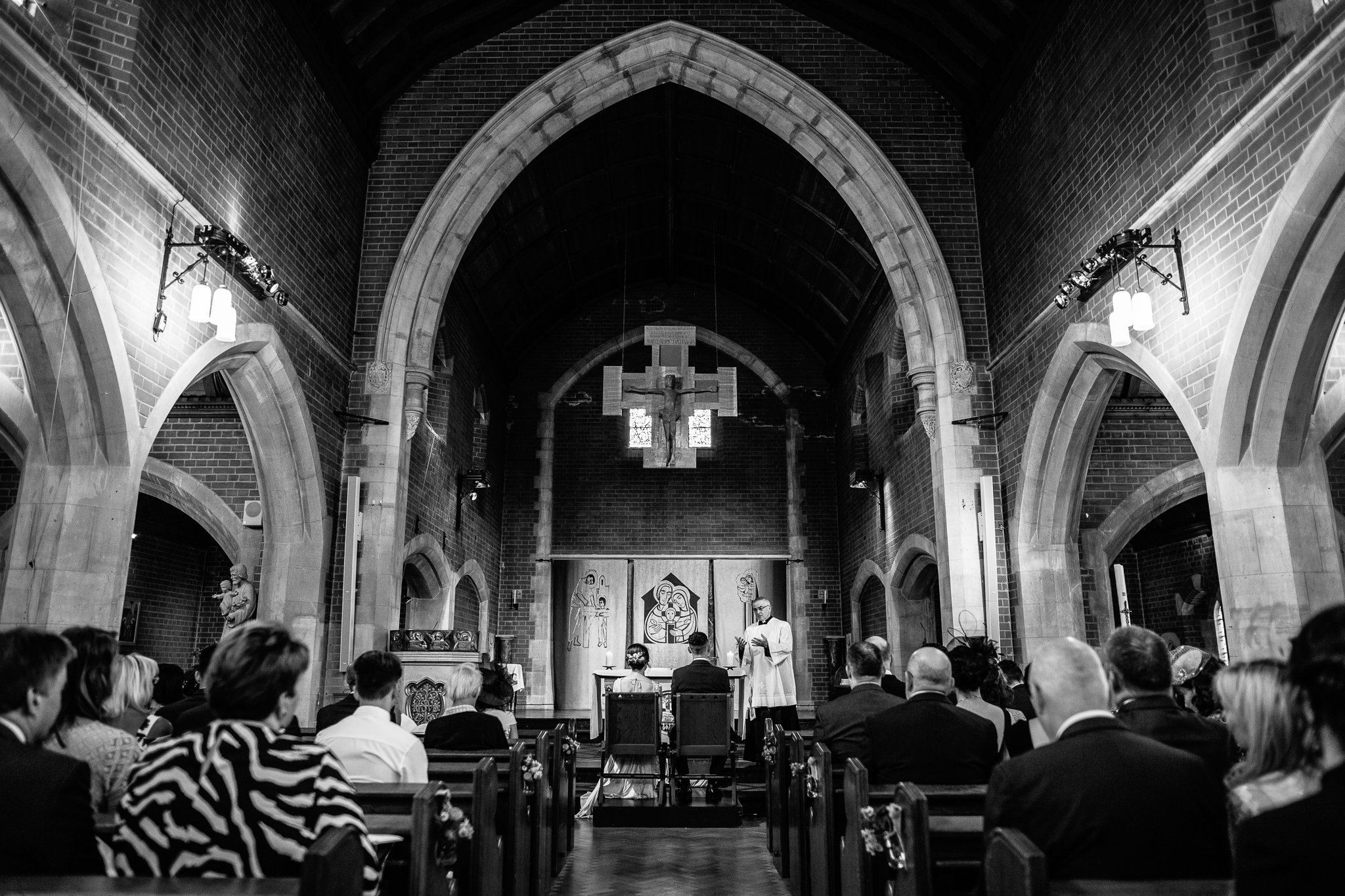  Bride and Groom seated as the Vicar addresses them at The Holy Family Church in Reigate 