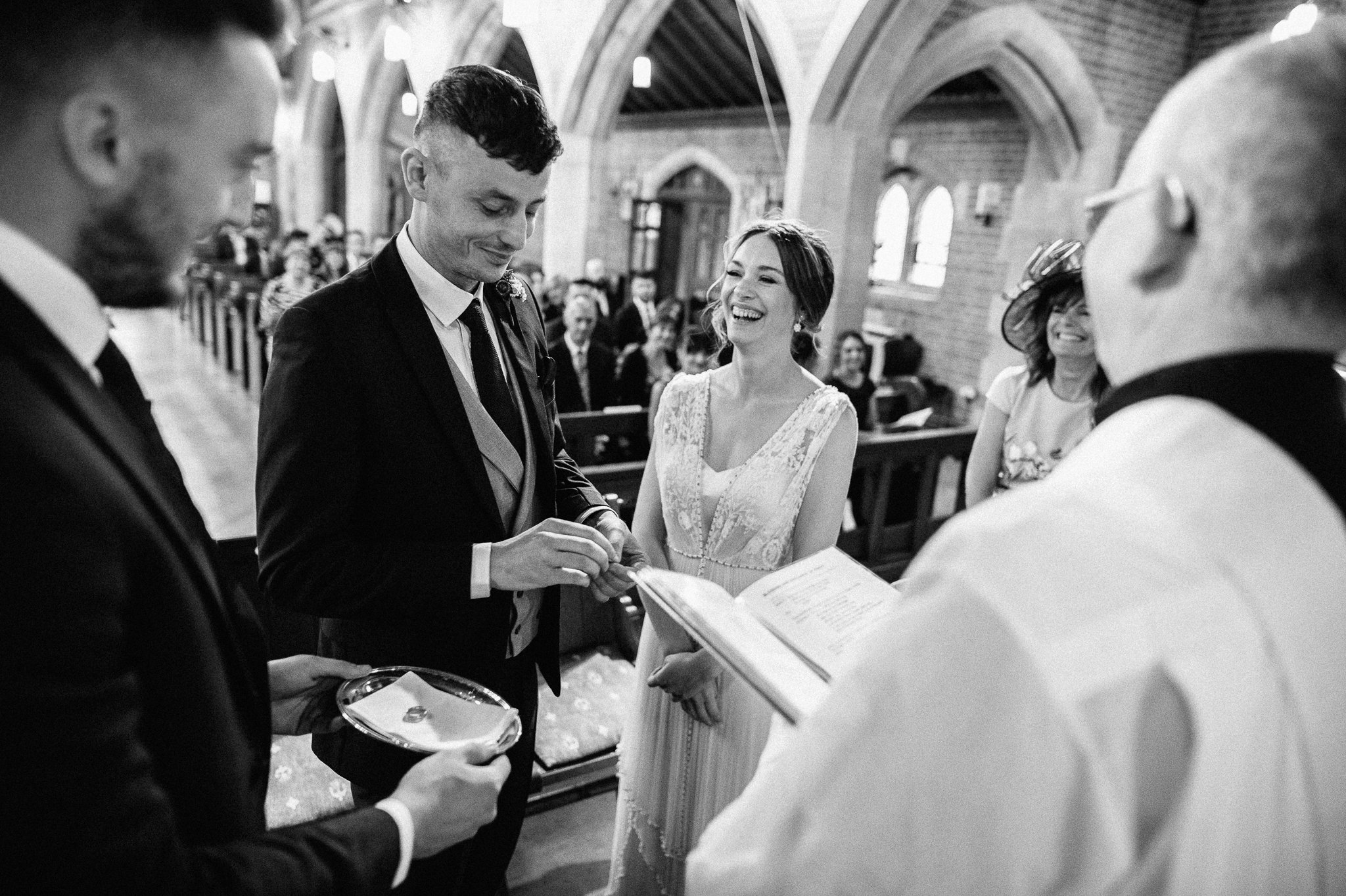  The Bride laughs at the groom whilst he is picking up the rings 