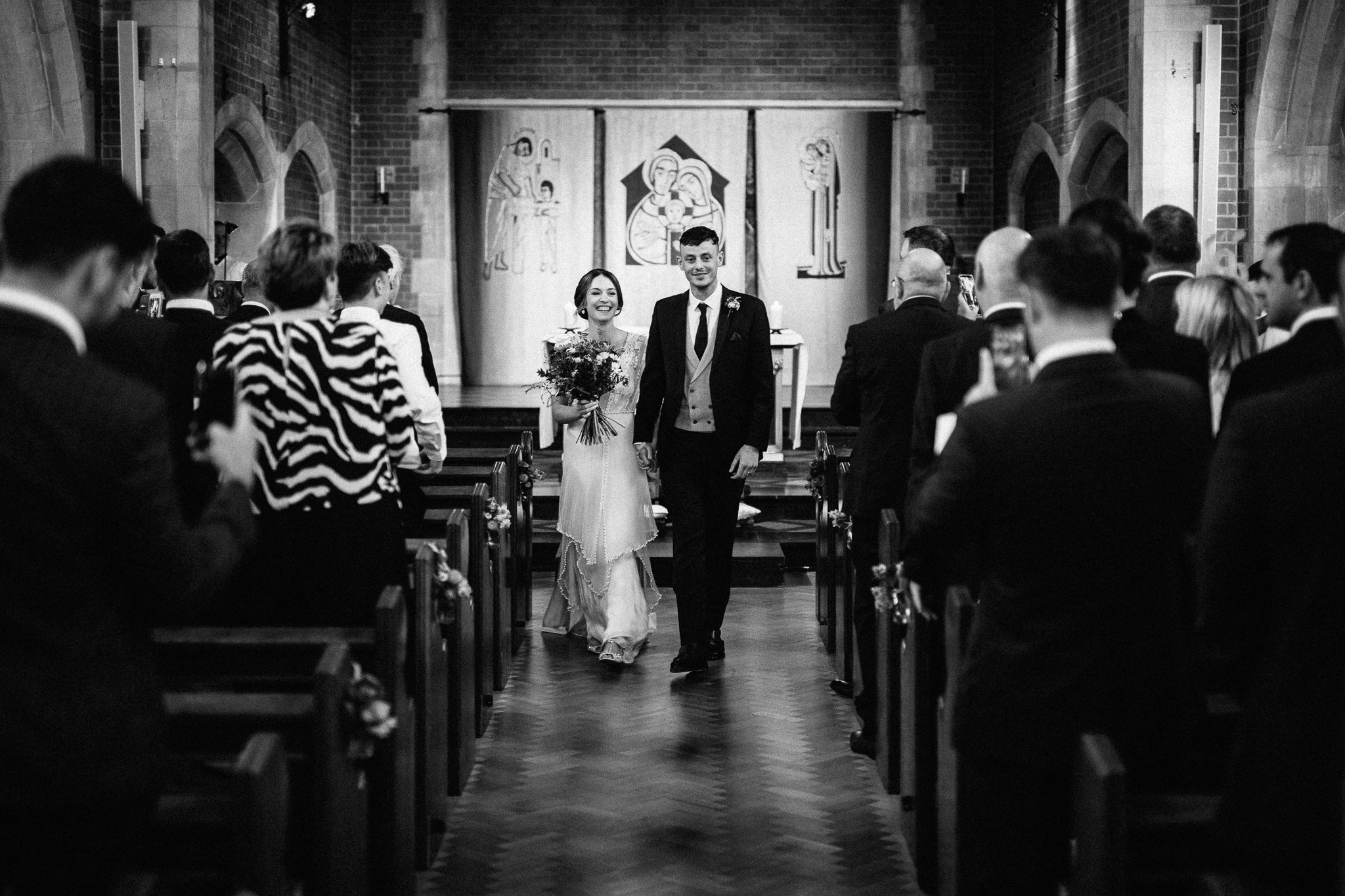  Bride and Groom walk down the aisle after being married at The Holy Family Church in Reigate 