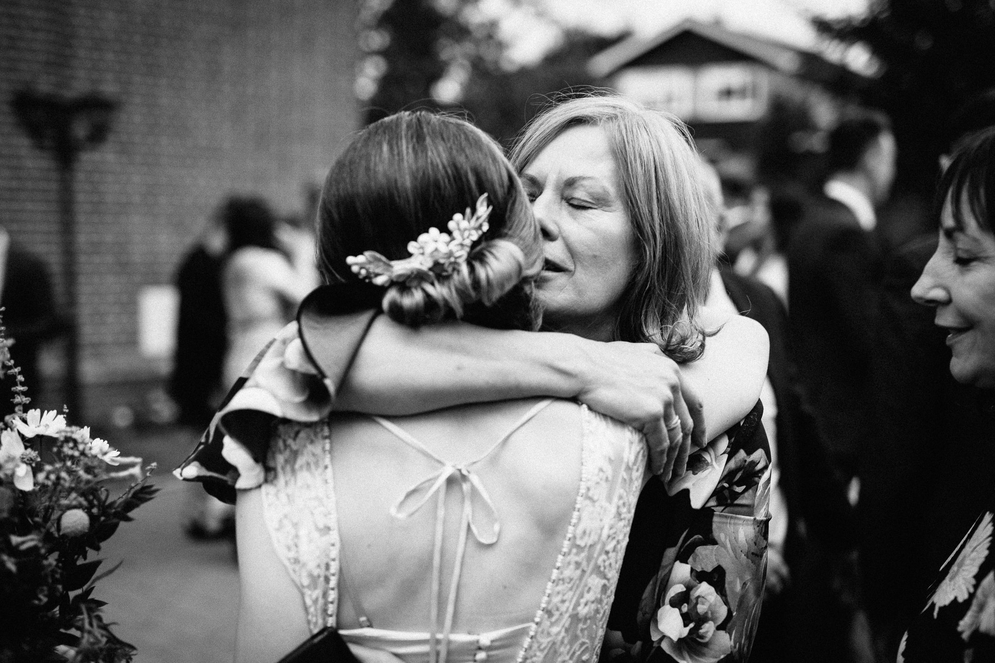  Guest hugs the bride outside The Holy Family Church in Reigate 