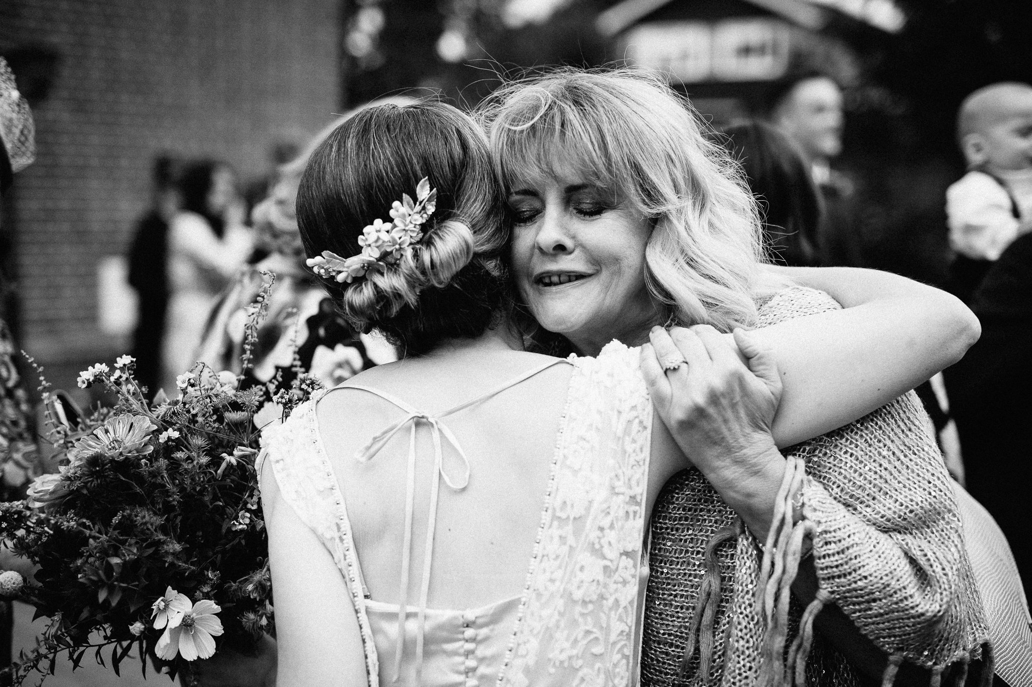  Bride hugs a guest outside The Holy Family Church in Reigate 