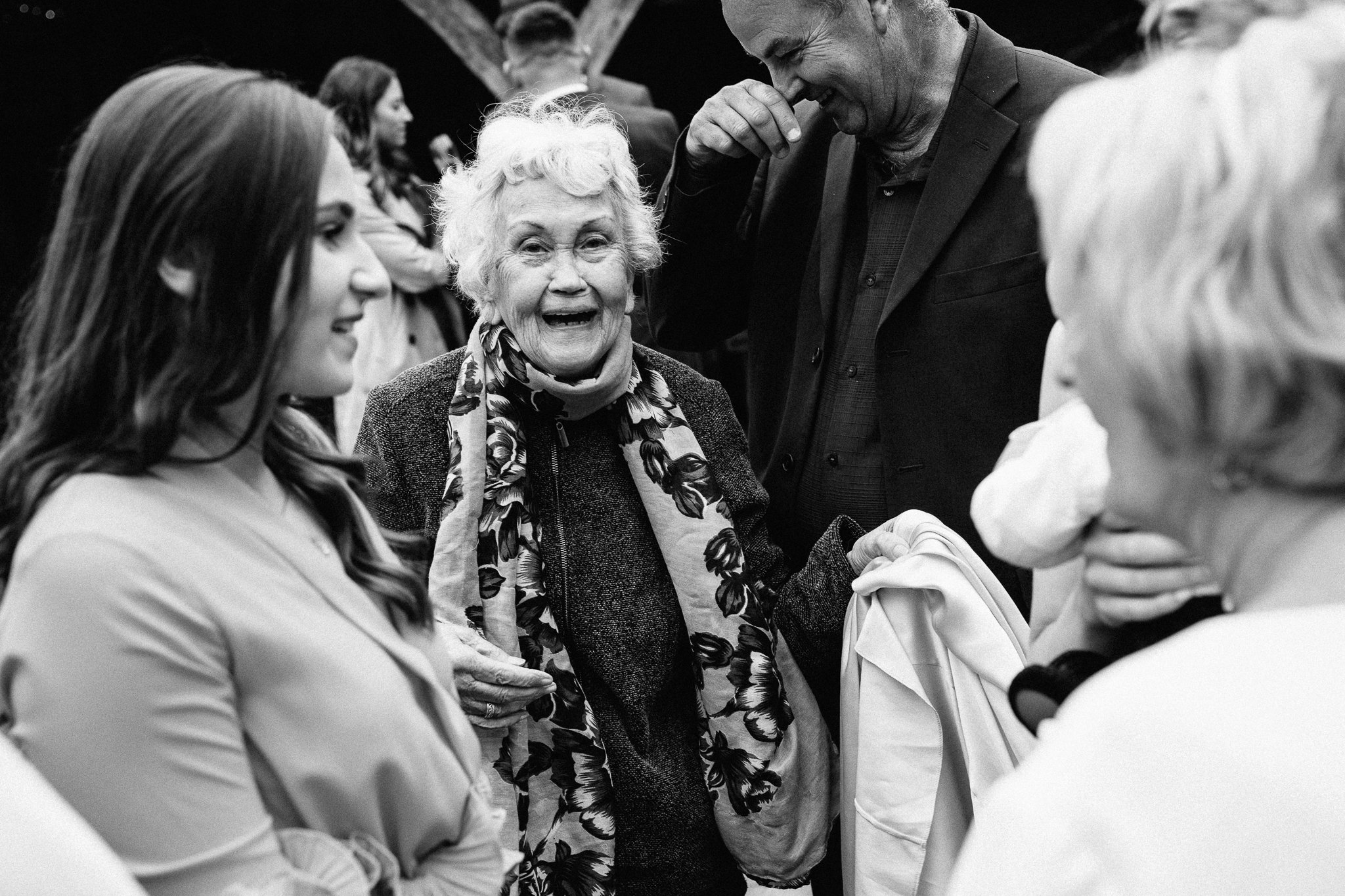  Elderly female wedding guest smiles at the camera at Gildings Barns in Newdigate Surrey 