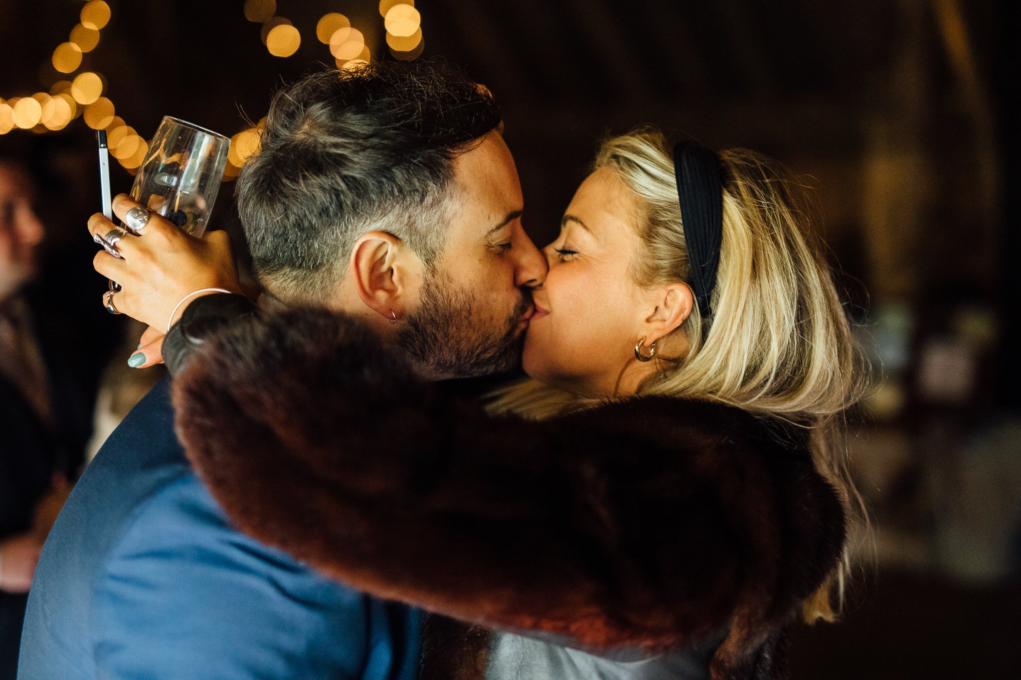  Two wedding guests kiss at Gildings Barns in Newdigate Surrey 