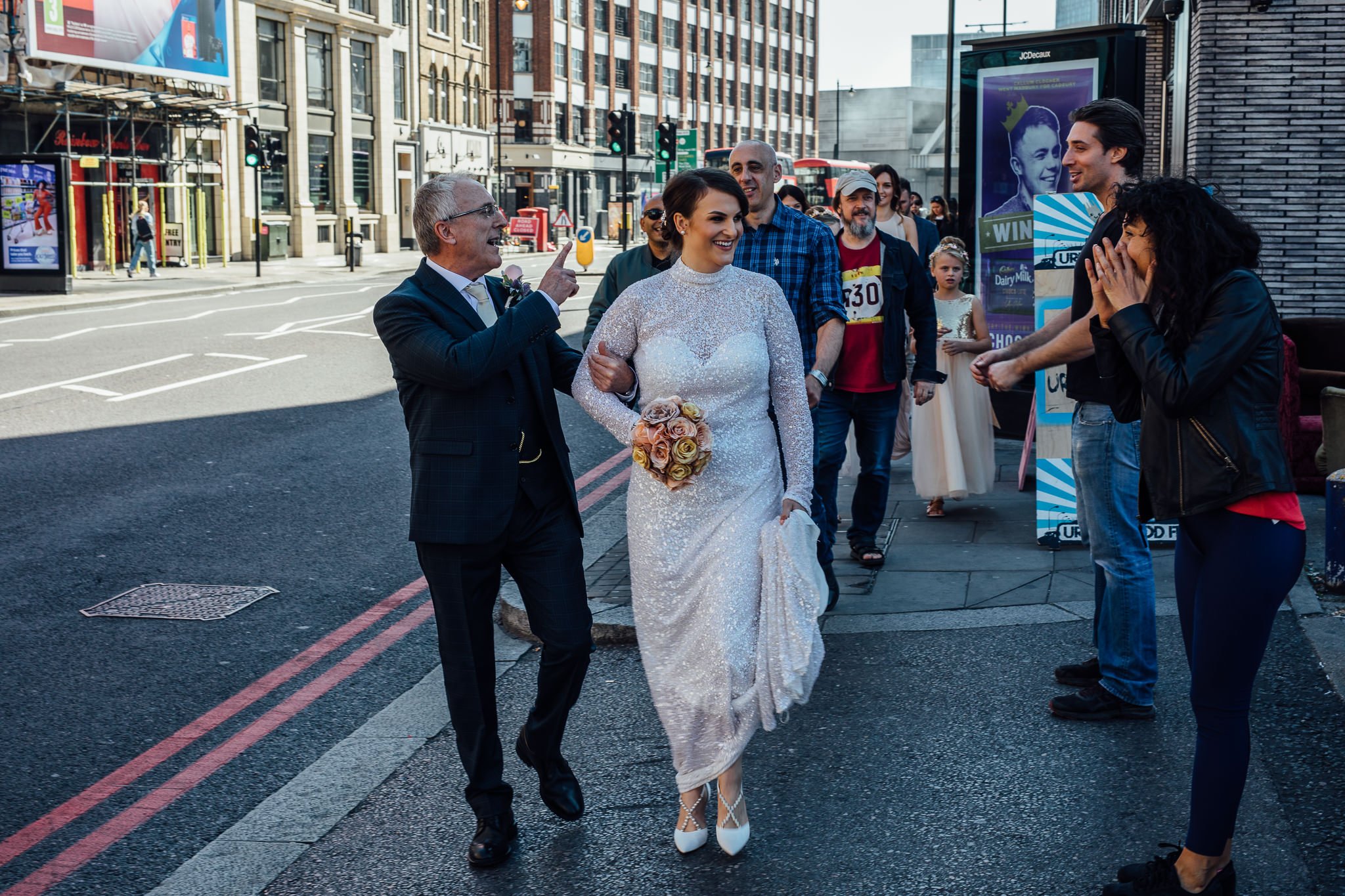  Bride walking down Shoreditch high street with her father whilst people wish them luck. 