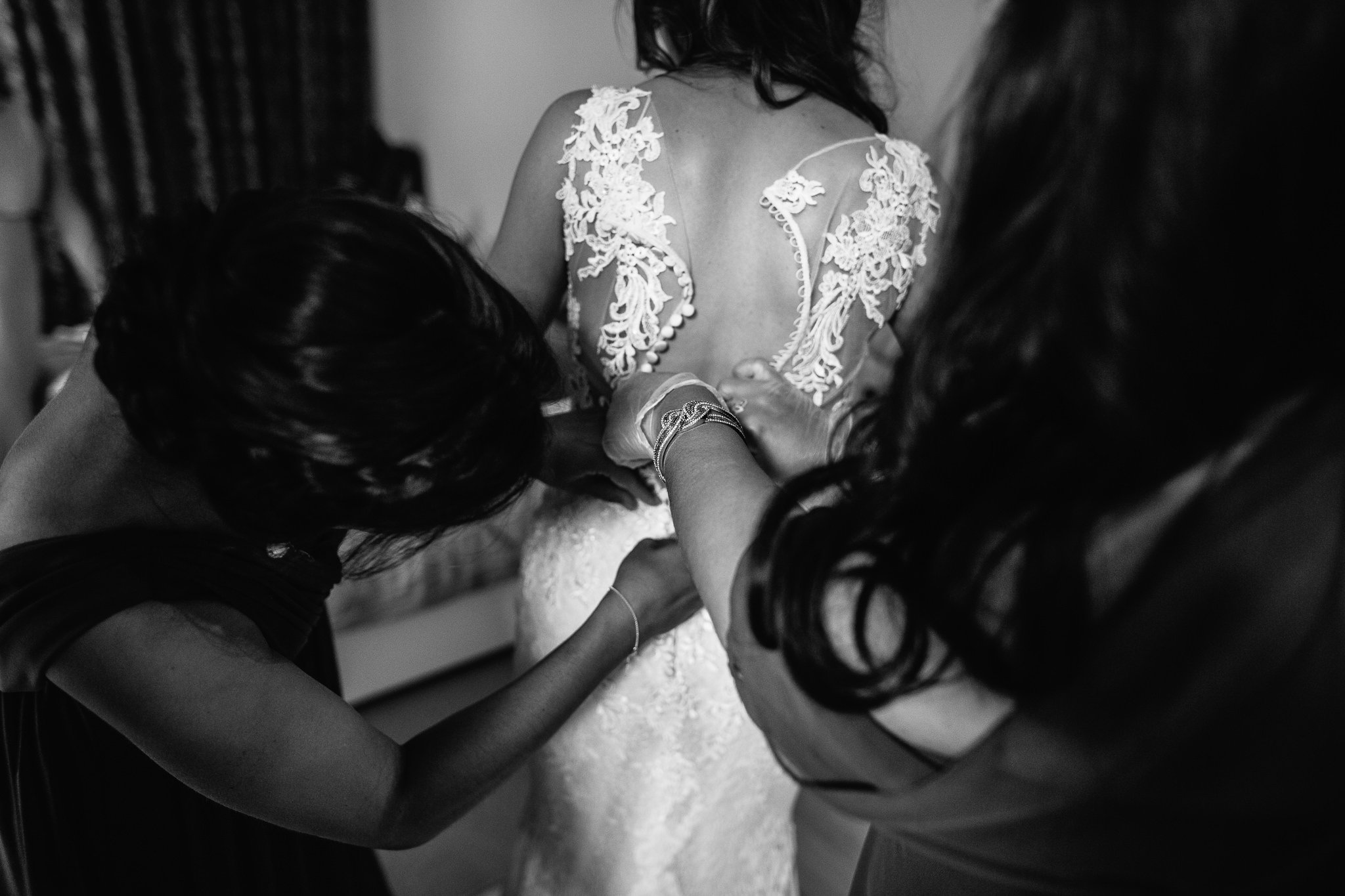  Bridesmaids help the Bride do her dress up at the back 