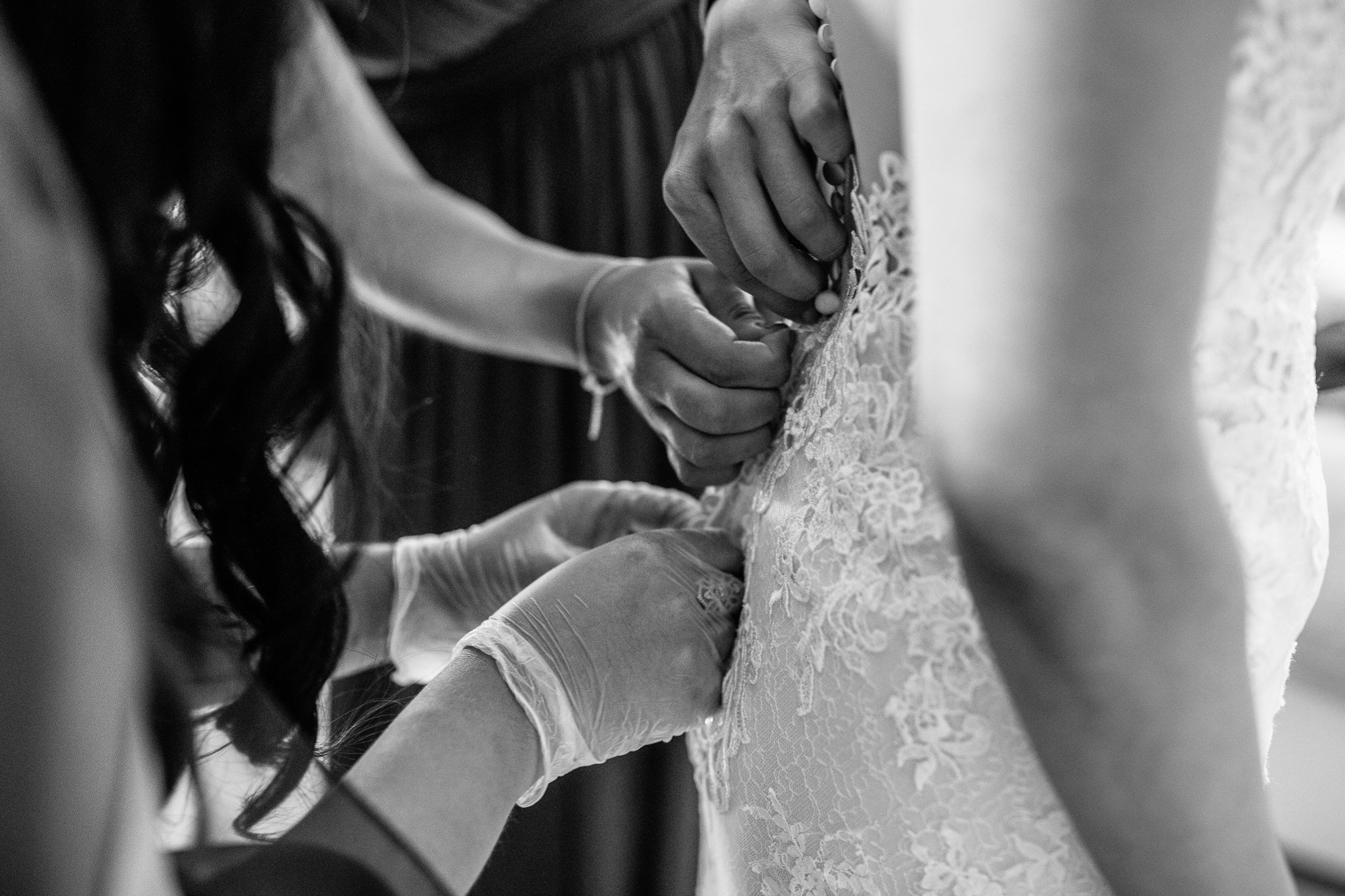  Hands securing the back of the bride’s dress 