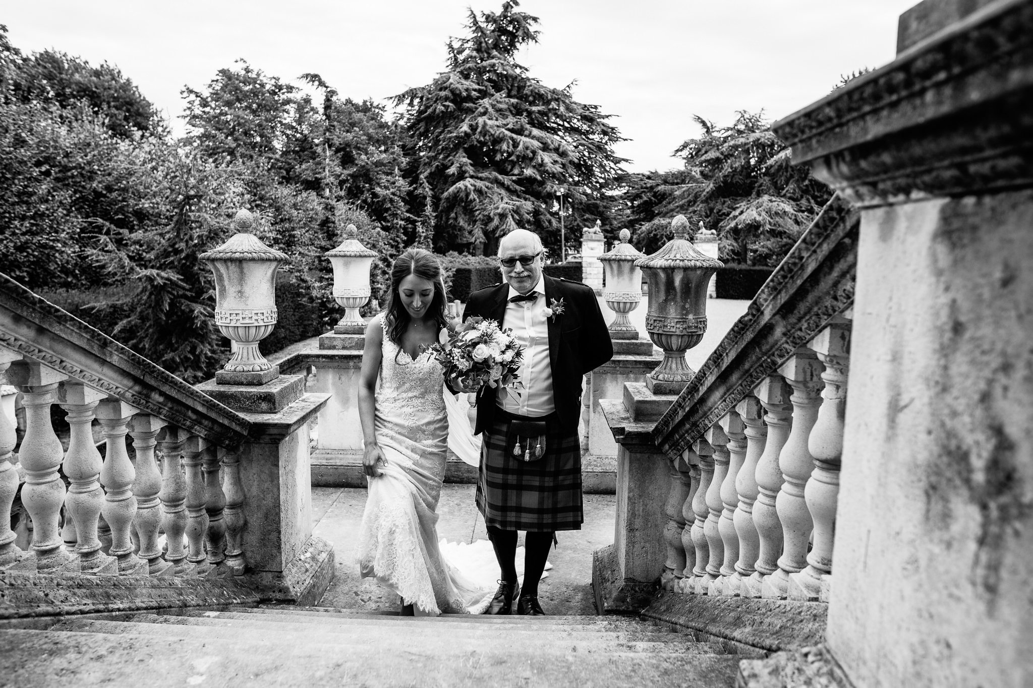  Bride walks up the stairs at Chiswick House with her father 